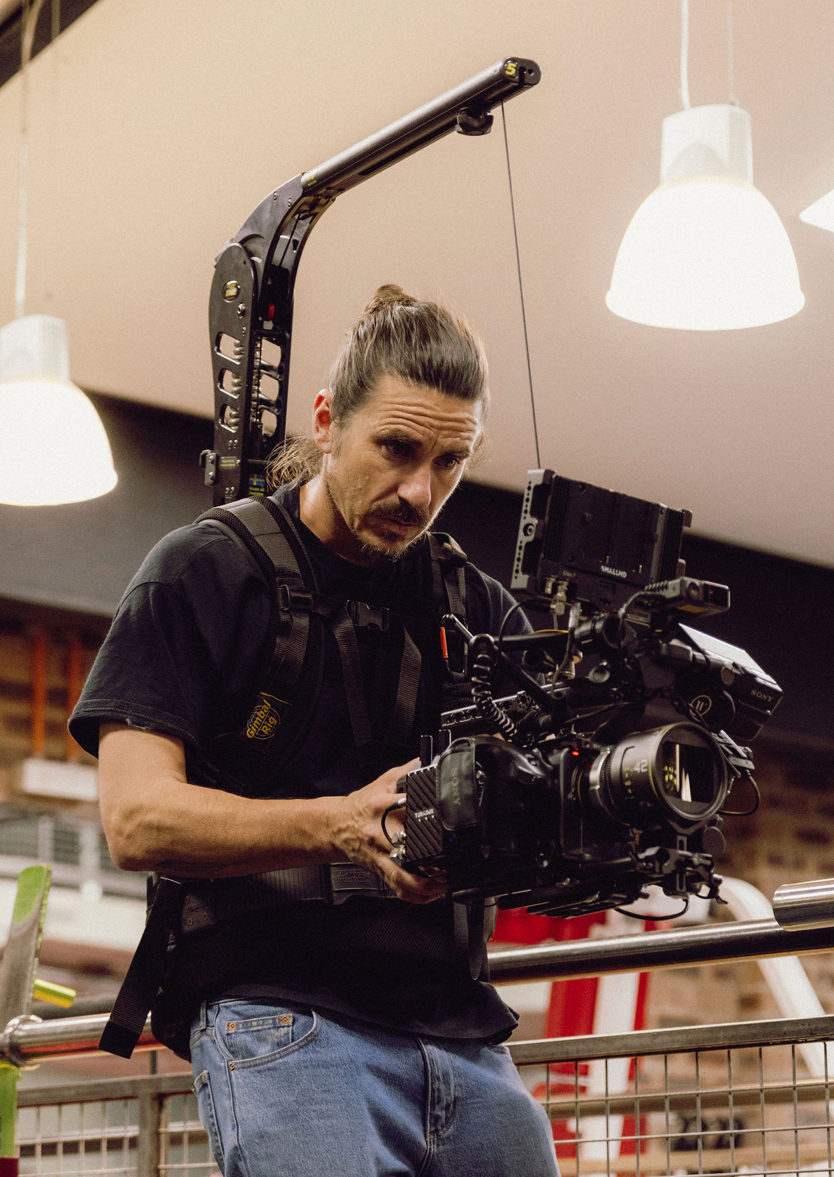 Camera operator filming with professional equipment in a brightly lit indoor space. Professional videographer in sydney