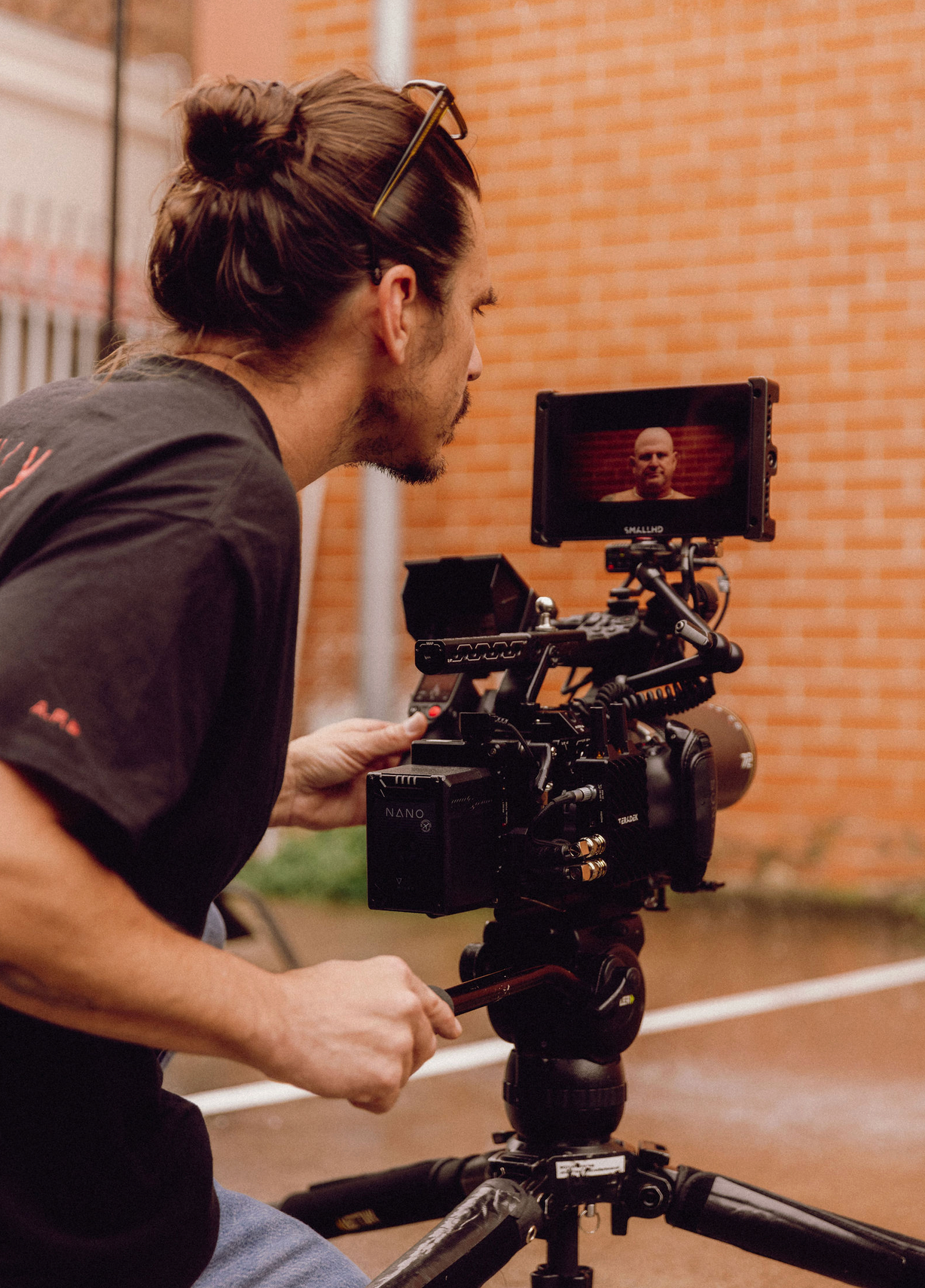 Cinematographer adjusts professional video camera settings during outdoor shoot. Professional videographer in sydney