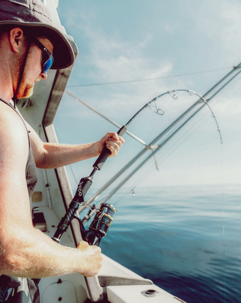 Wollongong videographer and photographer Person holding fishing rod and reel while deep sea fishing on a bright sunny day.