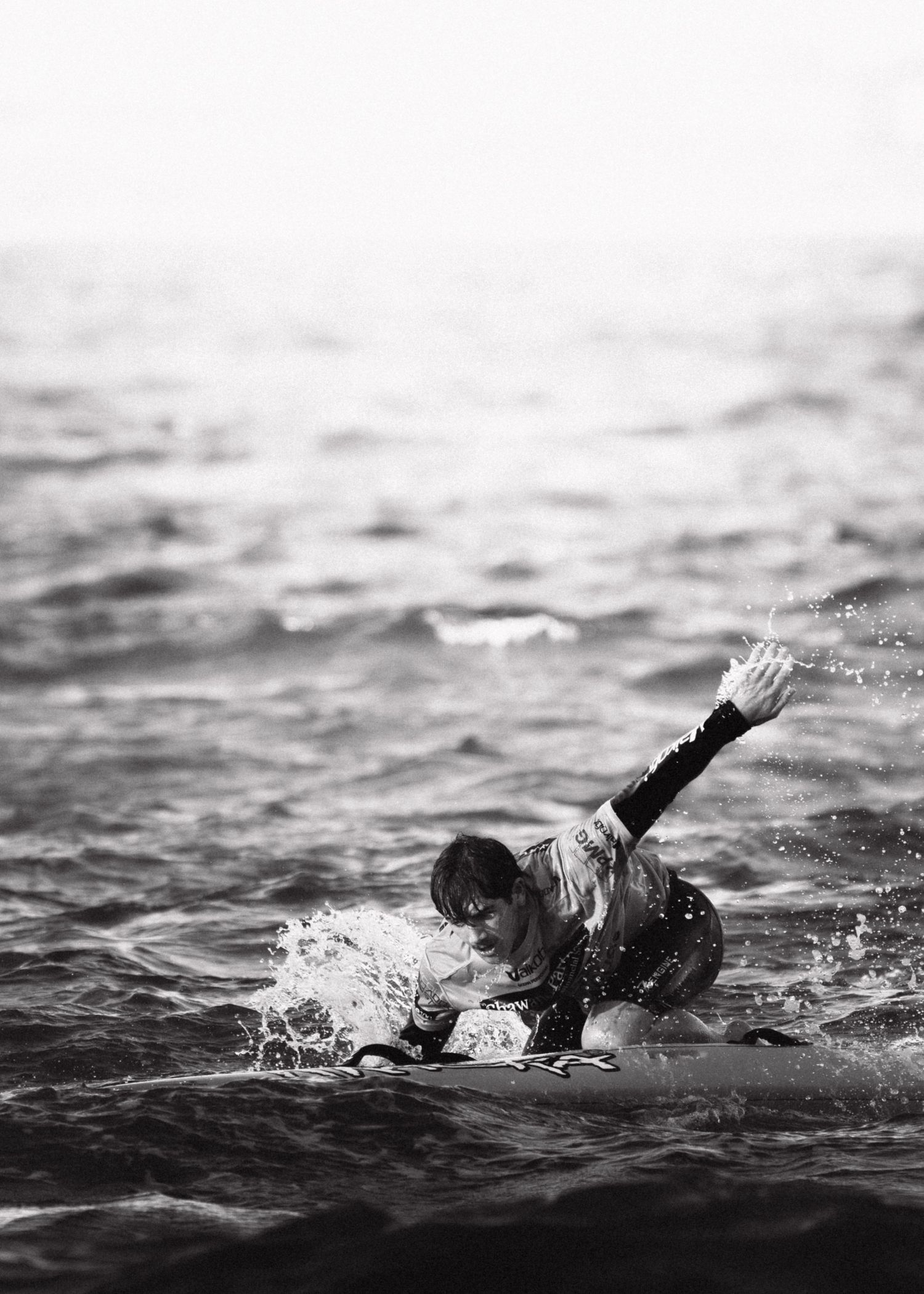 Sutherland Shire photographer and videographer Black and white image of surfer paddling through choppy ocean water.