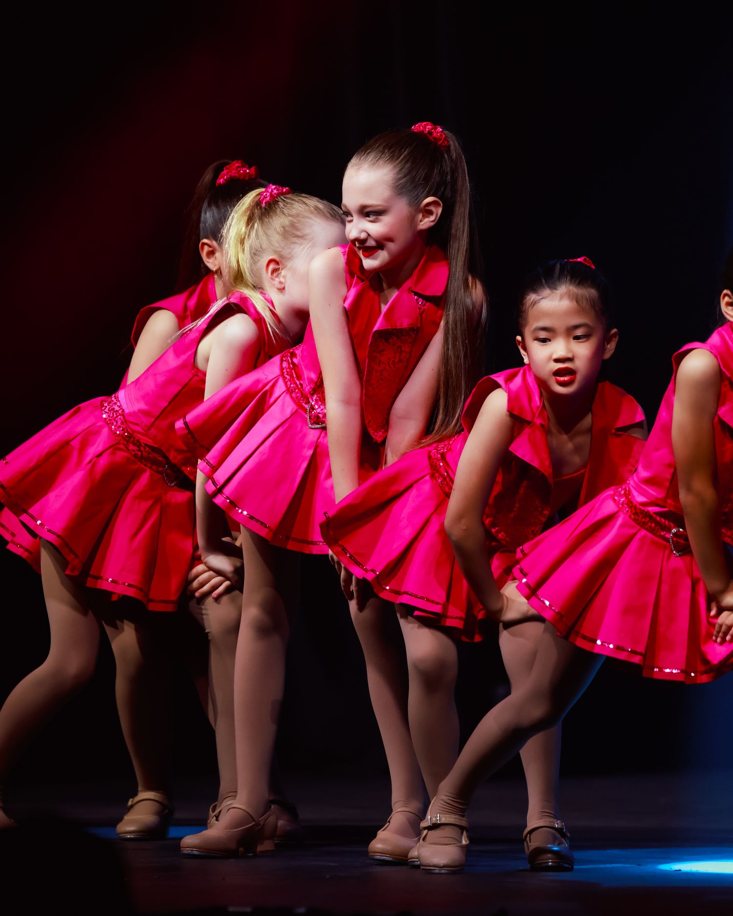 Sydney concert photographer Dance performers in matching hot pink dresses strike synchronized poses during a stage performance.