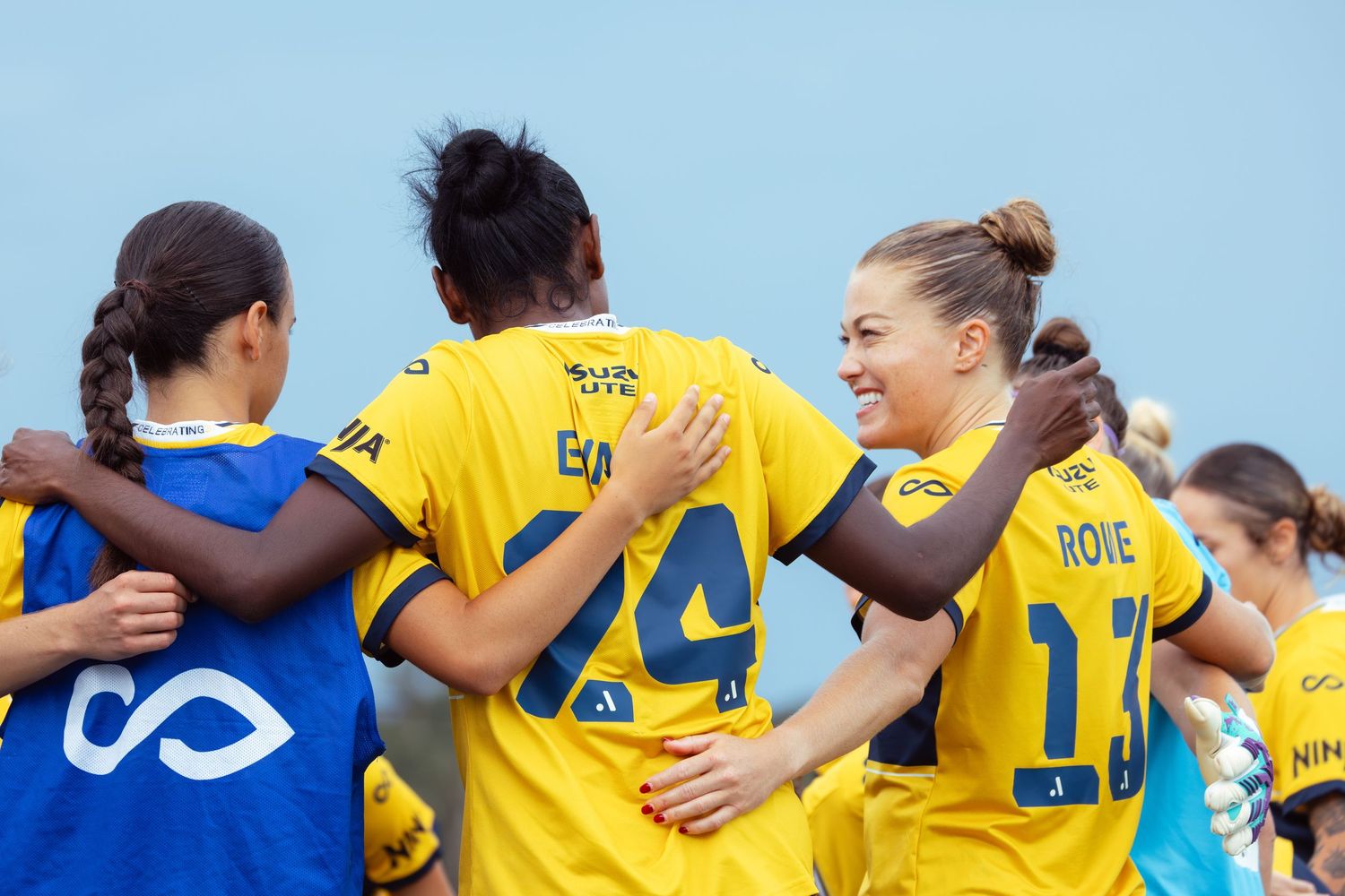 Wollongong photographer Soccer team celebrates together wearing yellow and blue uniforms on the field.