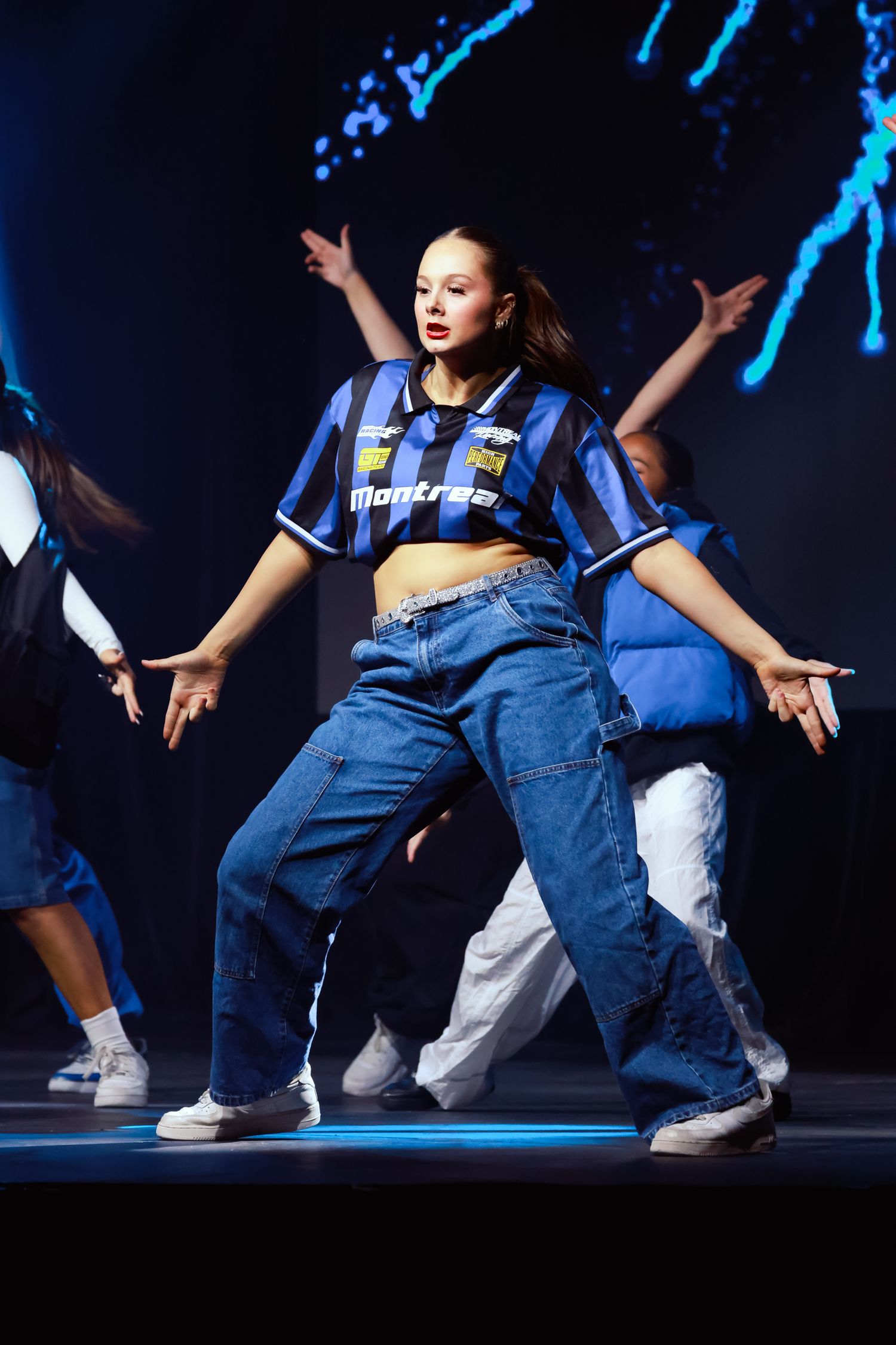 Sydney concert photographer and videographer captures Dancers in denim overalls perform synchronized street dance moves under blue lighting.