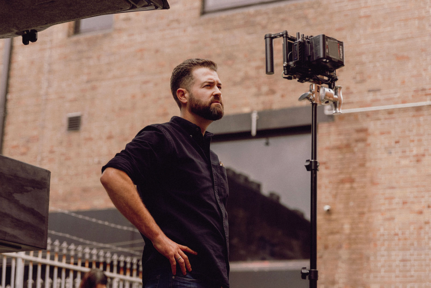 Camera operator films against brick wall exterior in natural lighting. Professional videographer in sydney