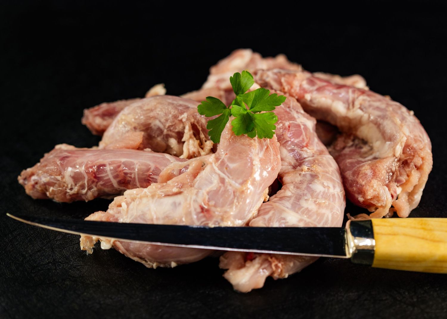 Raw pork ribs on a dark slate board with a wooden-handled knife and fresh parsley garnish. Sutherland Shire videographer