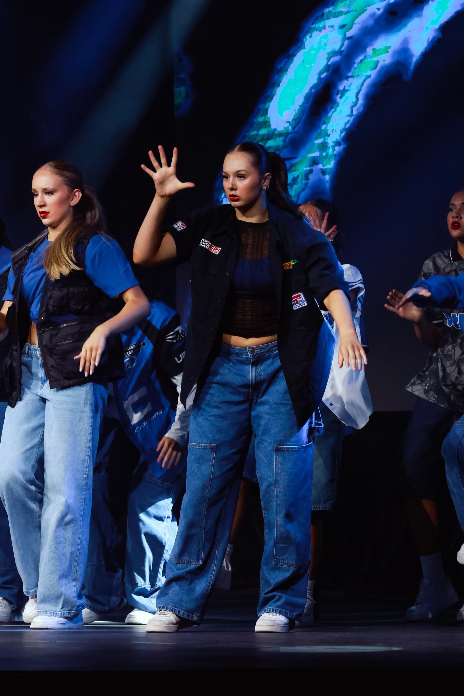 Sydney event photographer and videographer captures Dance ensemble performs synchronized routine in denim outfits under blue stage lights.