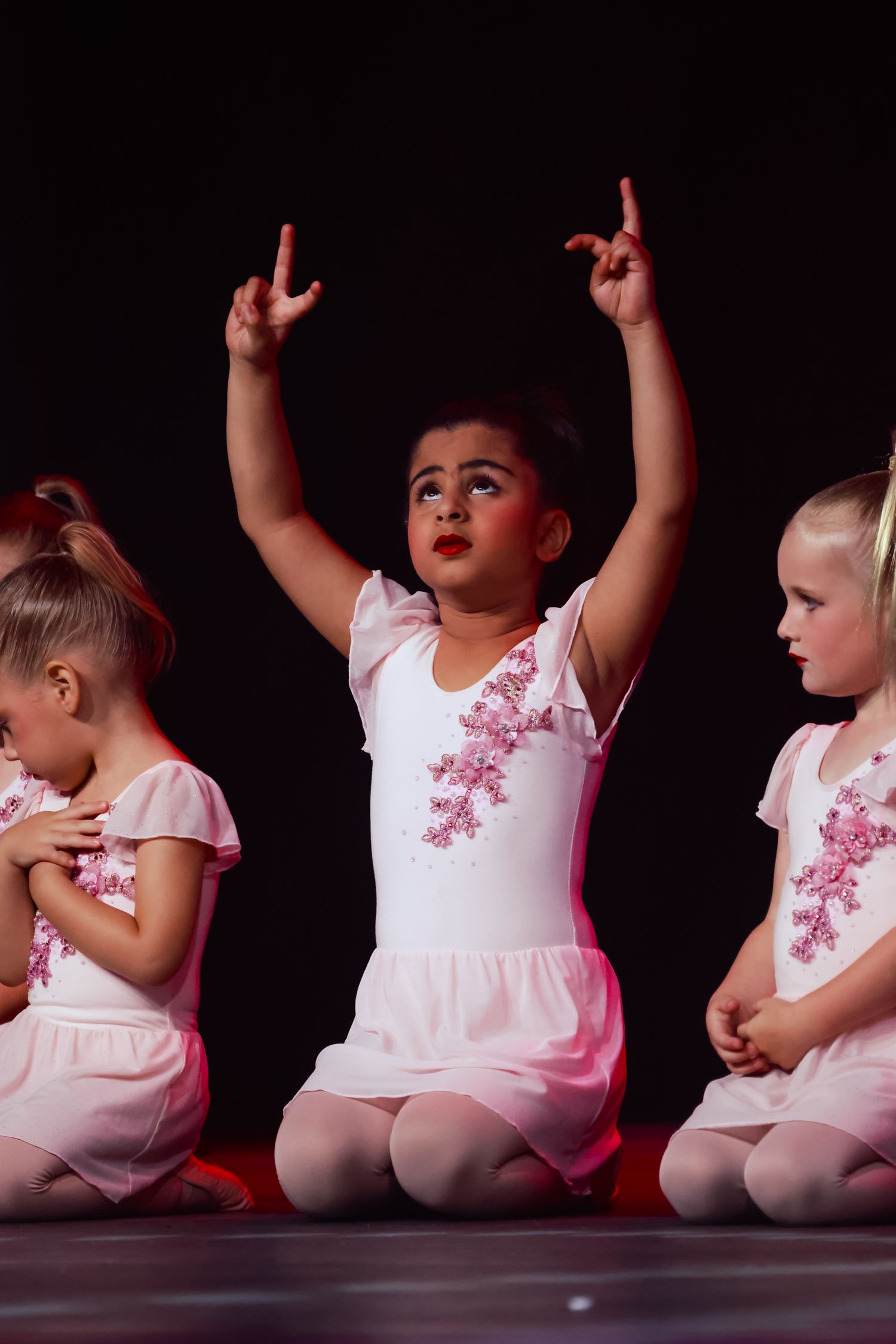 Wollongong concert photographer Young ballet dancers in white tutus sit together on stage during a performance.