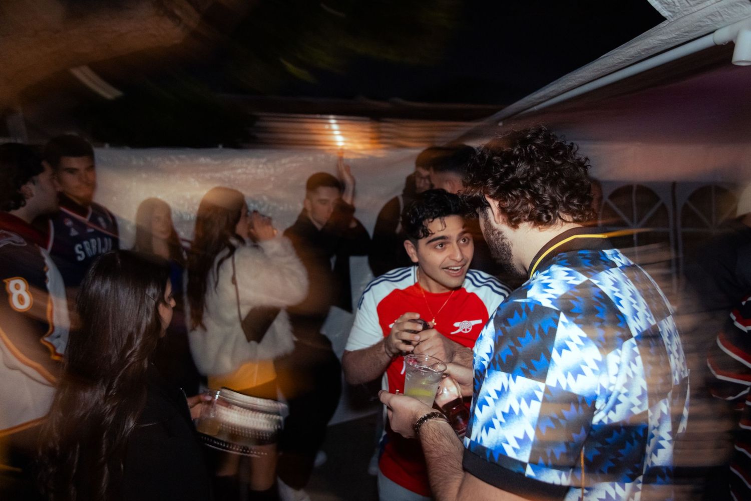 Group of young people socializing indoors at a lively party with motion blur effect.