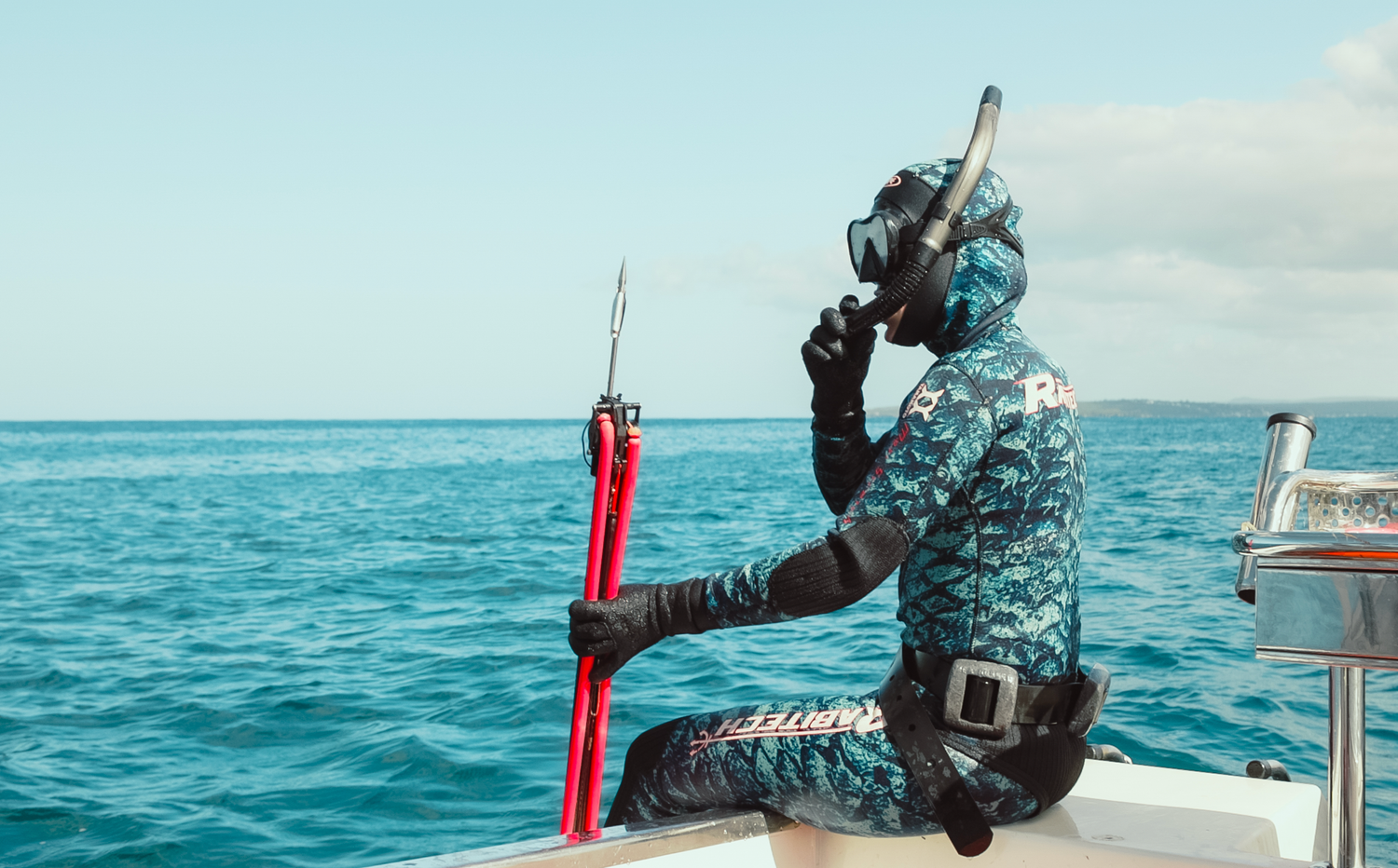 Spearfising diver with red equipment sitting on edge of boat during ocean excursion underwater photography in Cronulla, Sutherland, Sydney