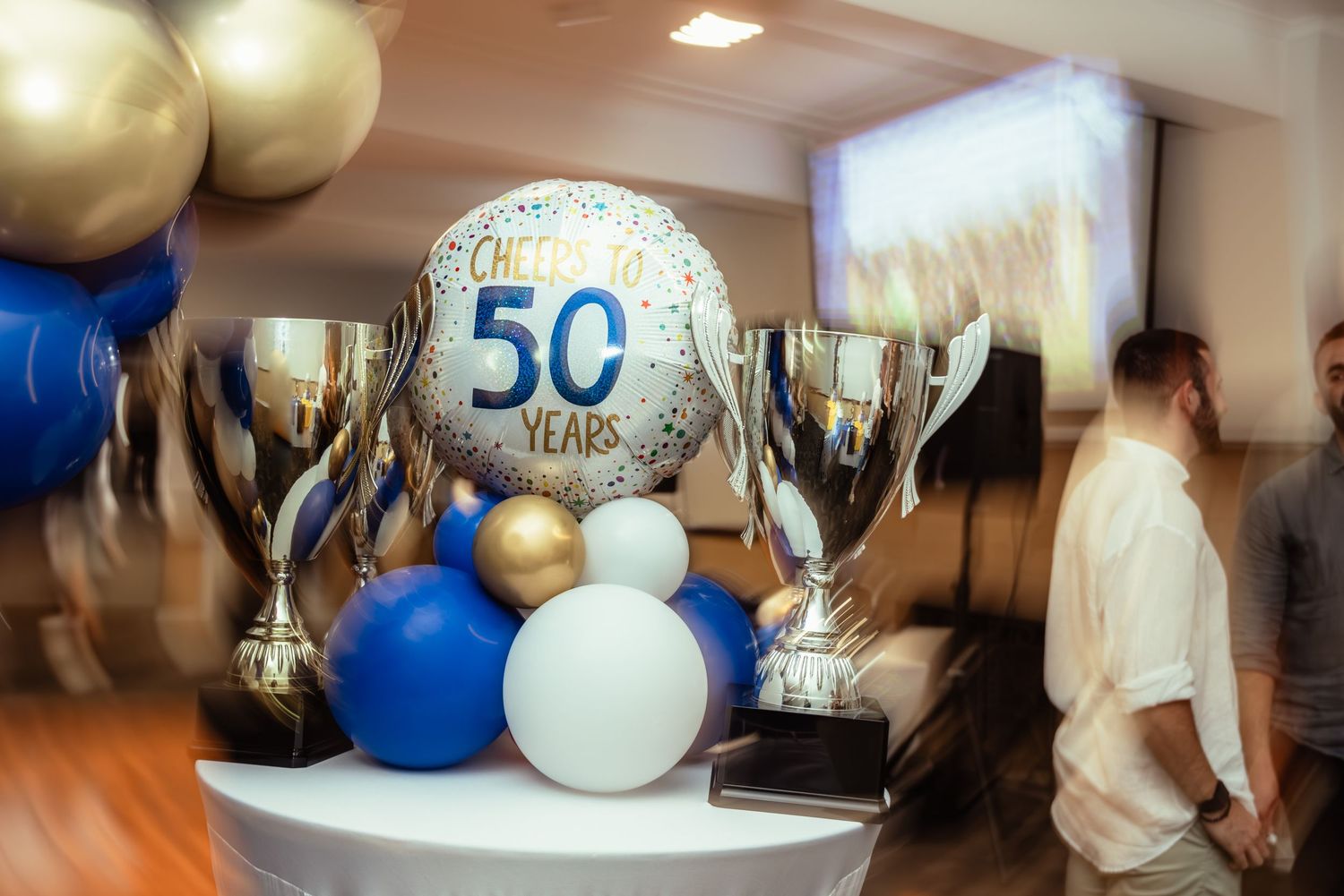 Golden trophies and balloons celebrating 50 years milestone anniversary at an elegant event venue.