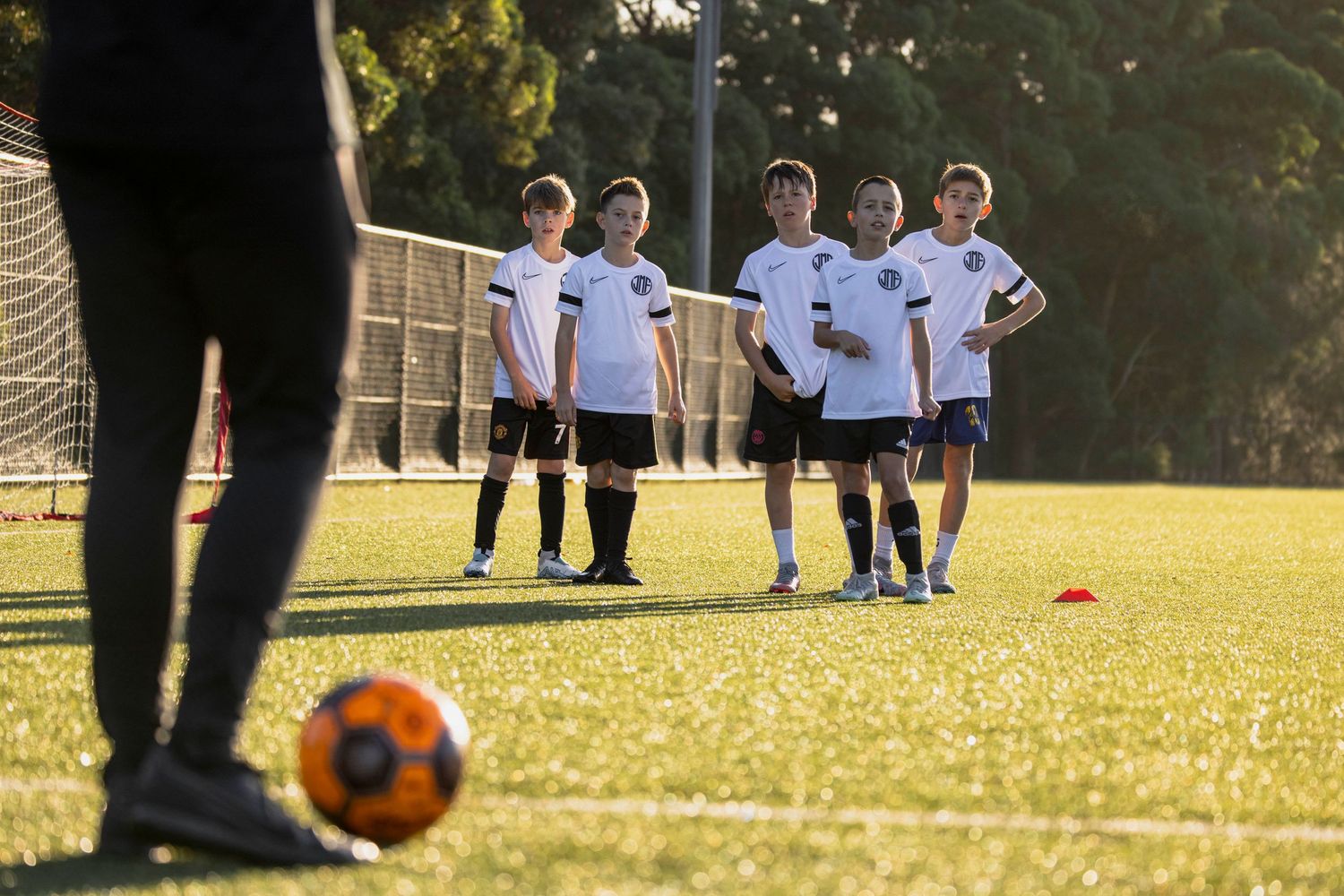 Sydney sports photographer captures Soccer players practicing drills on sunny grass field during training session.