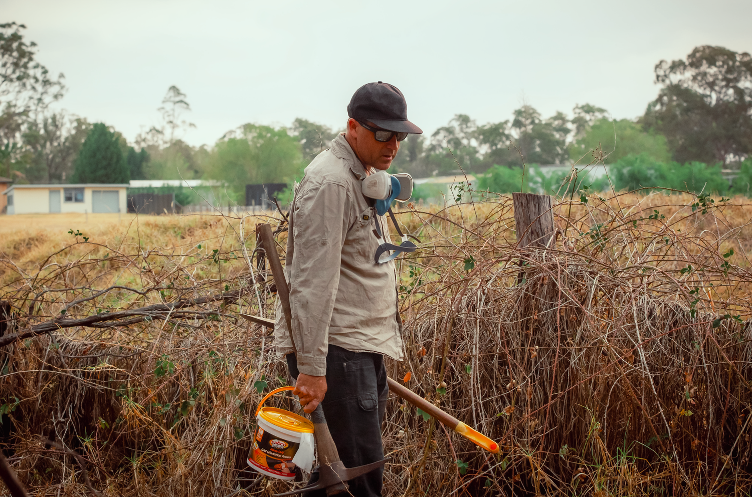 Branding and business photography and videography Worker in protective gear clearing brush and vegetation with power tools in a rural field.