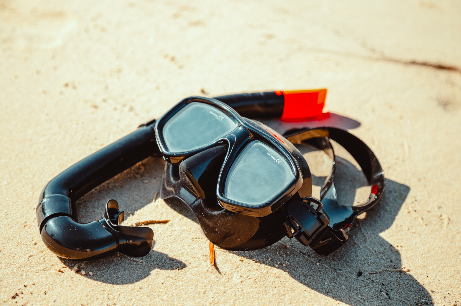 Close-up professional product photograph Sunglasses and diving gear casting shadows on sandy beach.