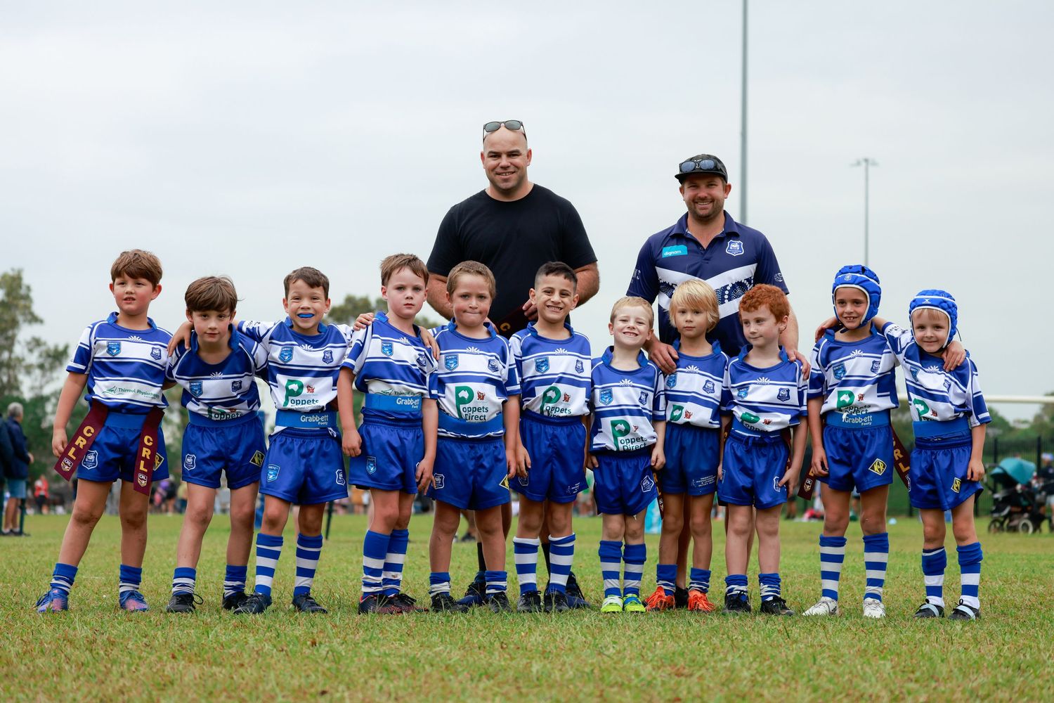 Wollongong and Illawarra sports photographer capturesYouth rugby team posing with coaches in blue and white striped uniforms.