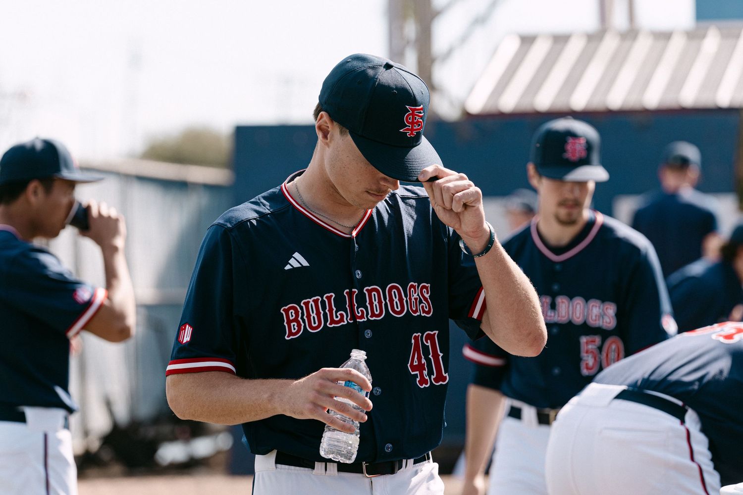 Baseball players in black uniforms gather in dugout during game discussing strategy and reviewing plays.