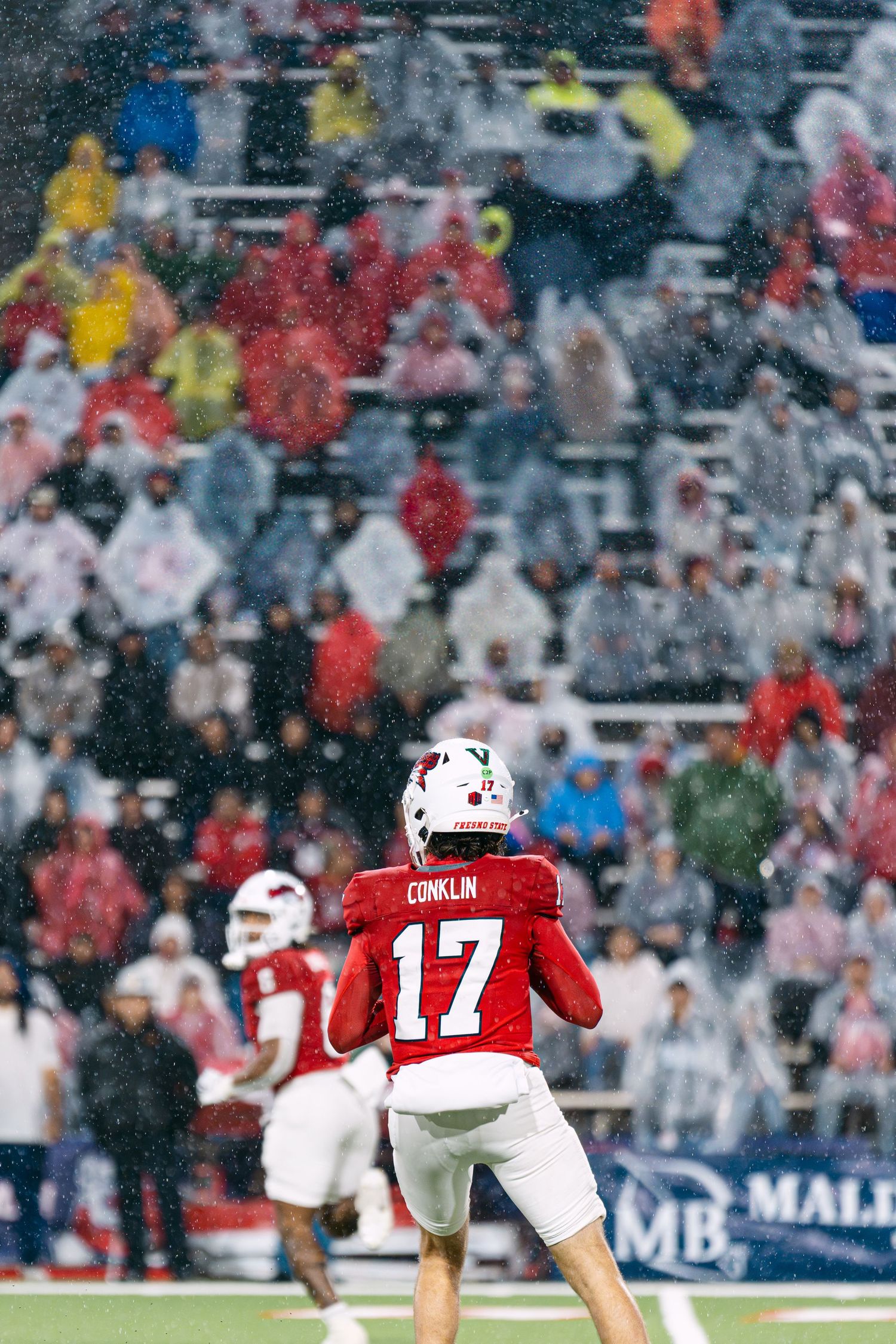 Football player in red jersey number 17 runs down field during game with crowd in background.