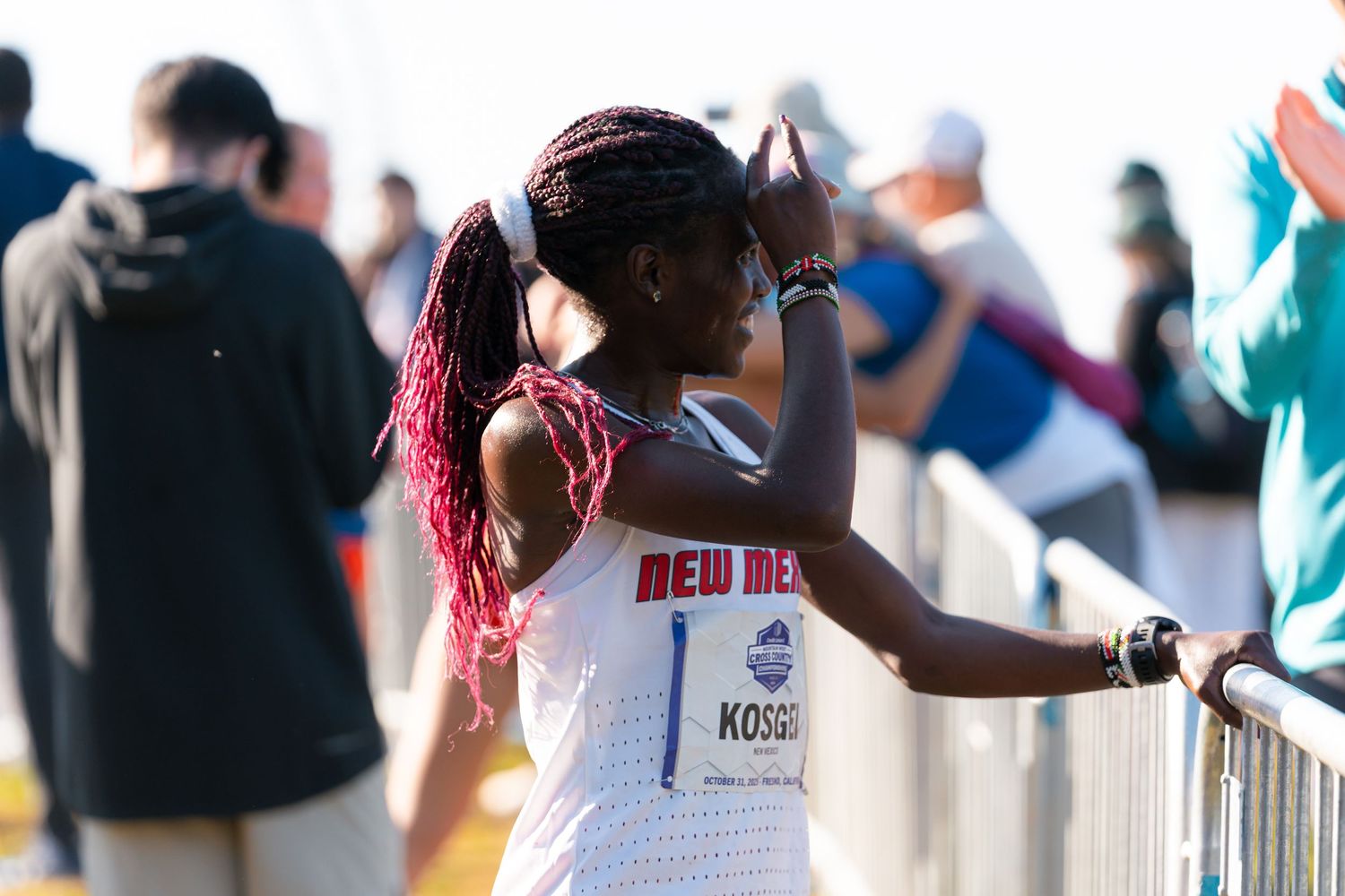 Runners participate in a marathon event along a crowded street lined with spectators and support staff.