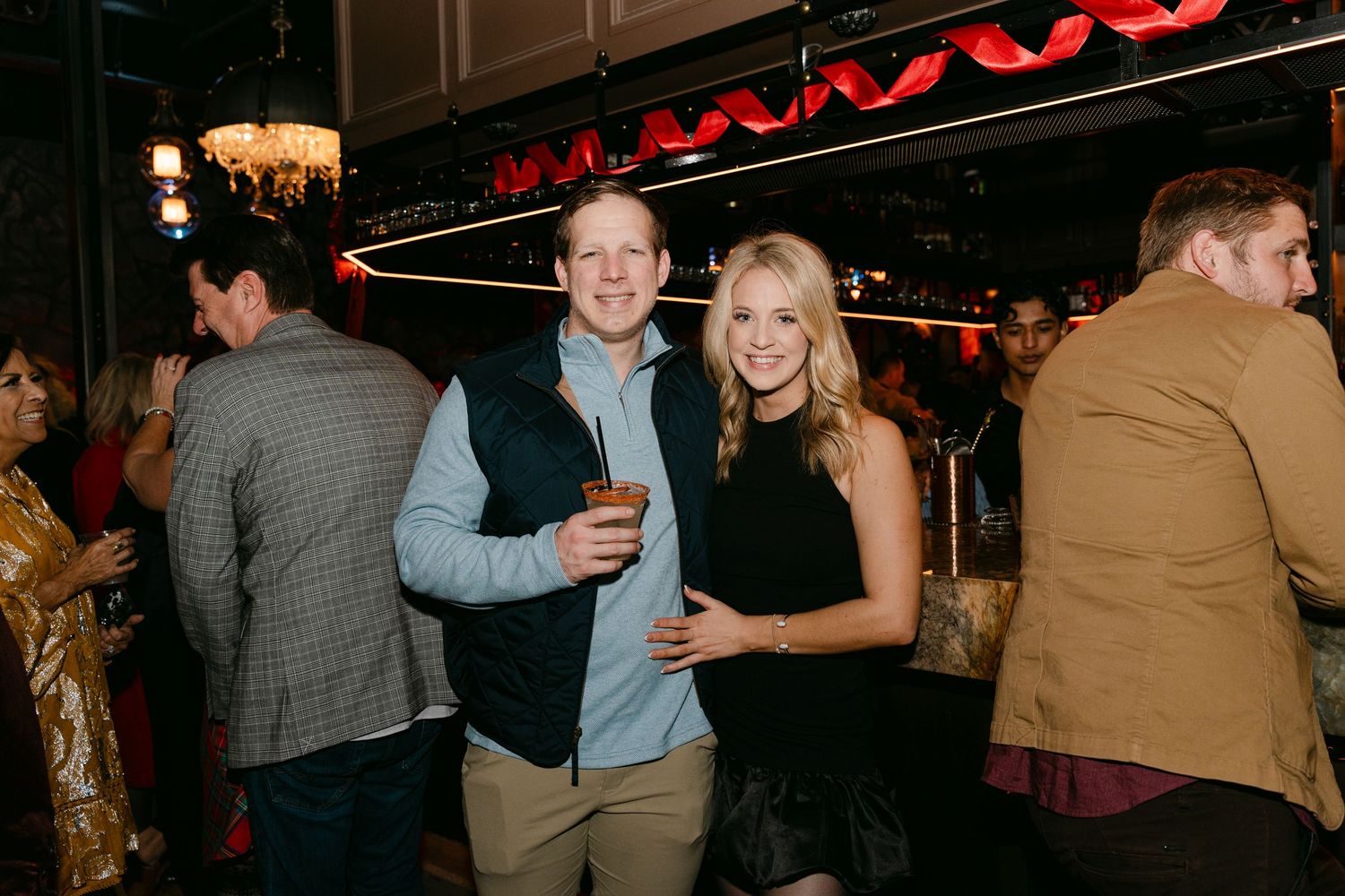Guests socializing in a dark venue with red neon lighting accents.