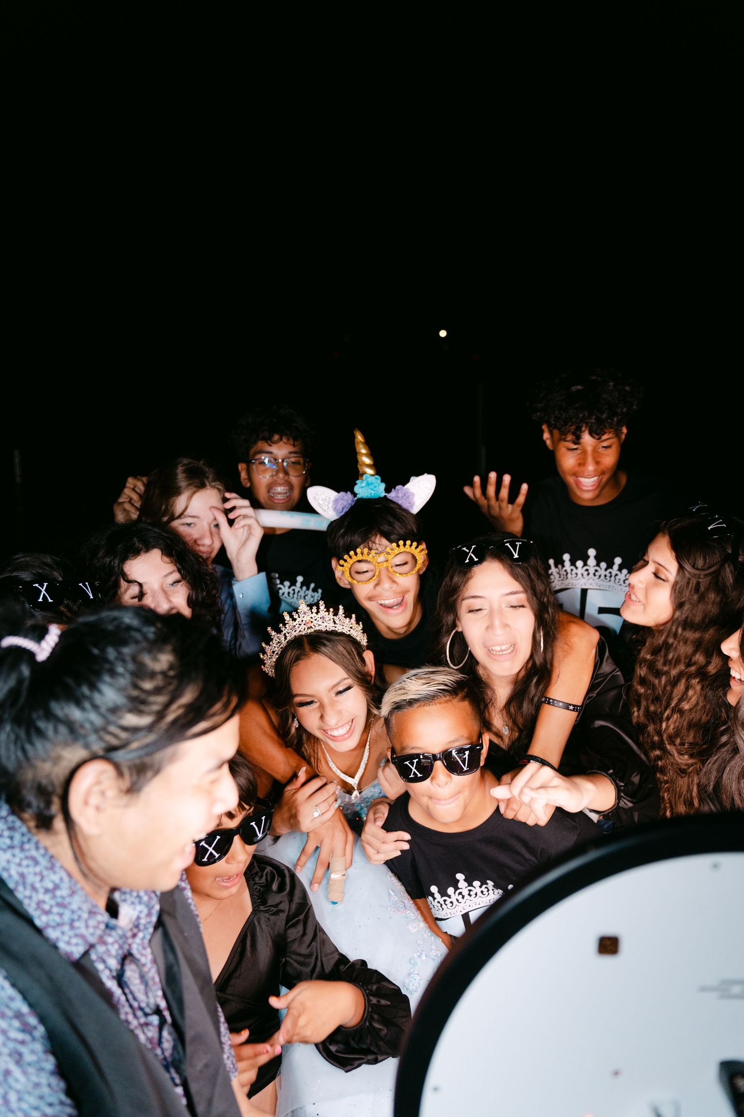 Festive group huddles together for a nighttime photo wearing party accessories.