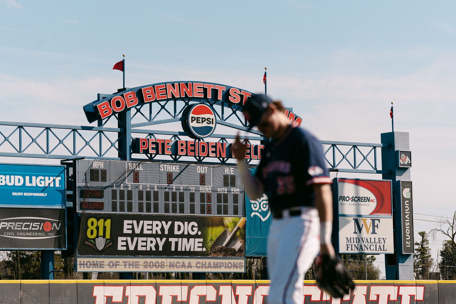 Aerial view of a baseball stadium with vintage-style signage and advertisements along the outfield wall.