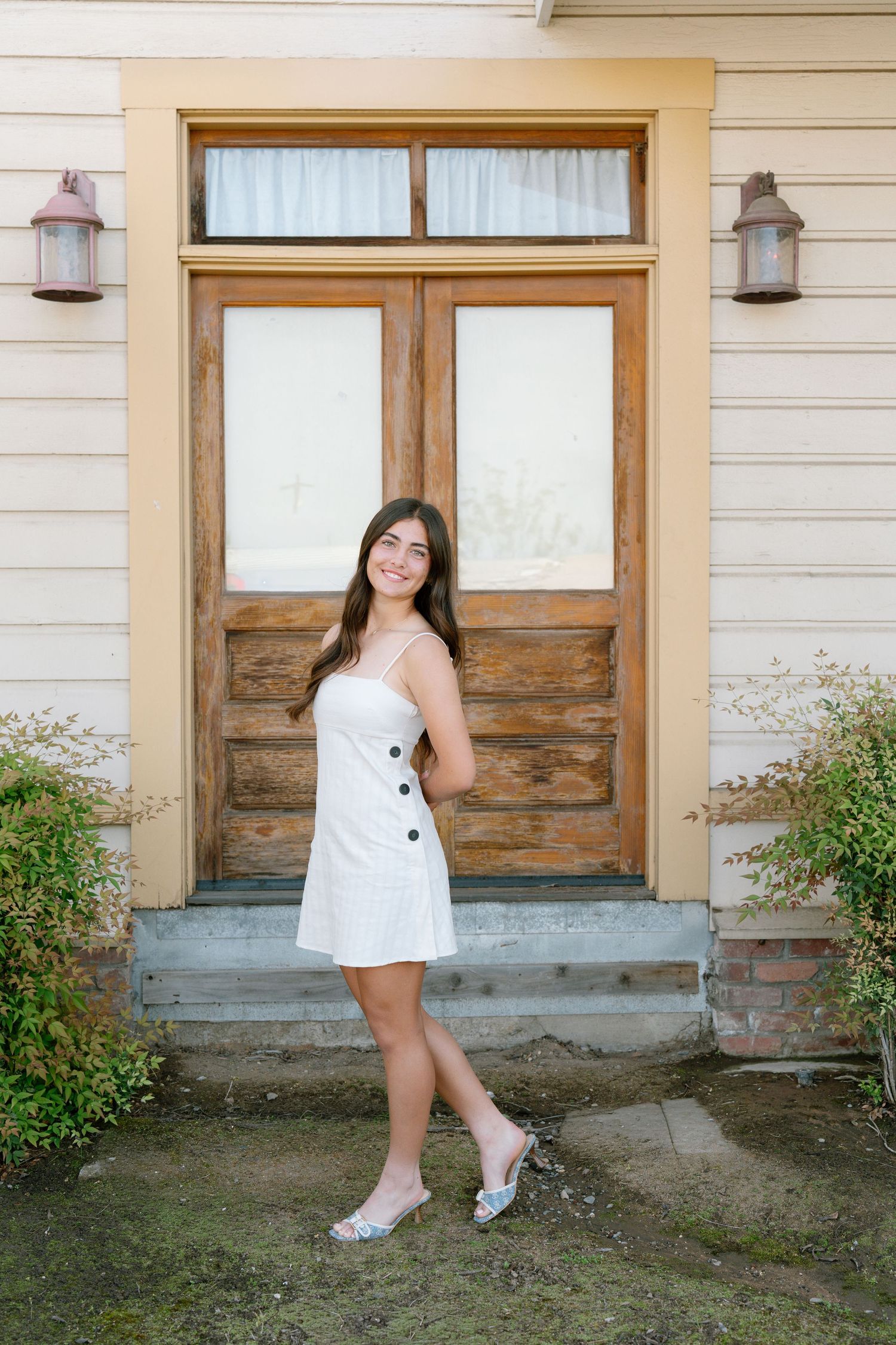 A series of four photos showing someone in a white dress and sneakers posing against a rustic building exterior.