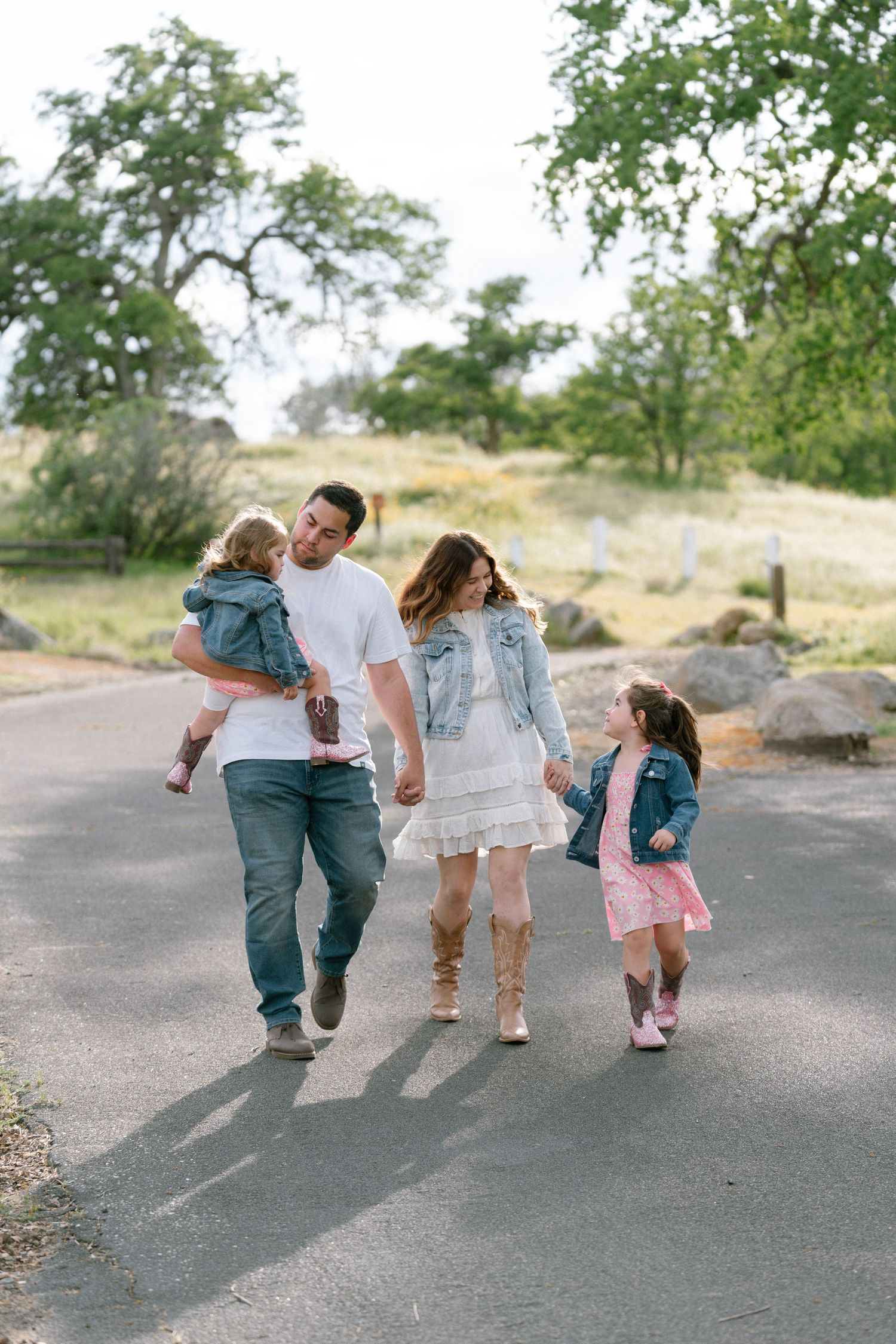 Family walking and playing together on a paved path outdoors.