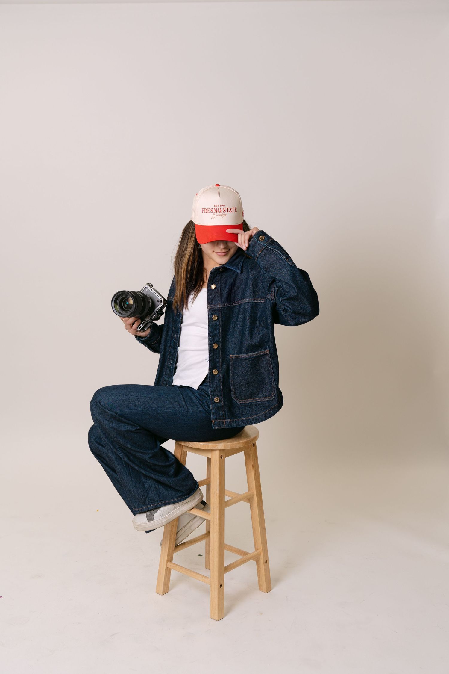 A sequence of photos showing a person in denim clothing sitting on a wooden stool in different poses against a white backdrop.