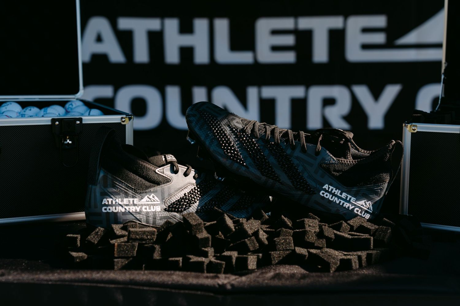 Athlete Country Club branded trail running shoes displayed on dark rocky terrain with logo backdrop in dramatic lighting.