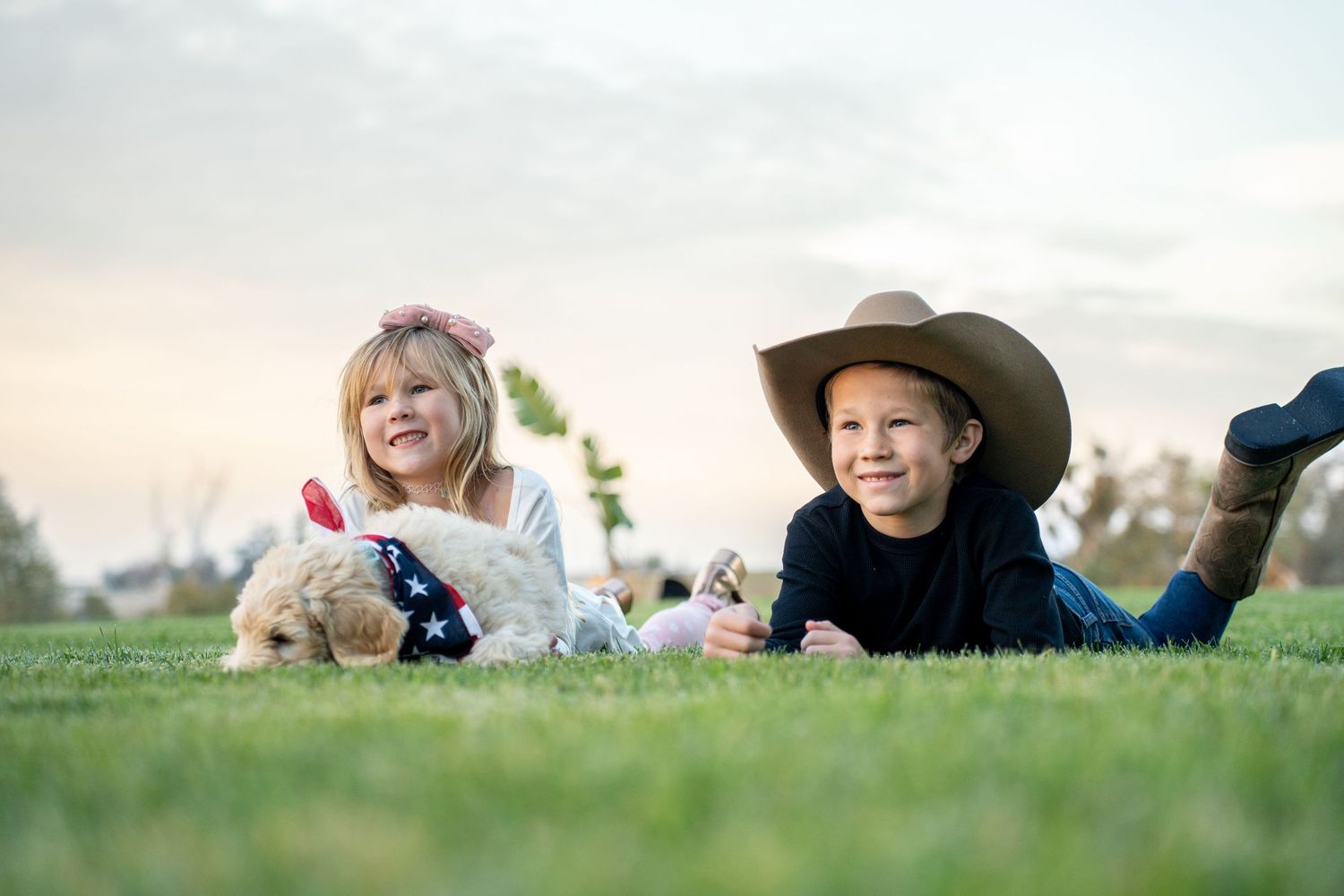 People lying down on grass wearing cowboy hats during a casual outdoor photoshoot.