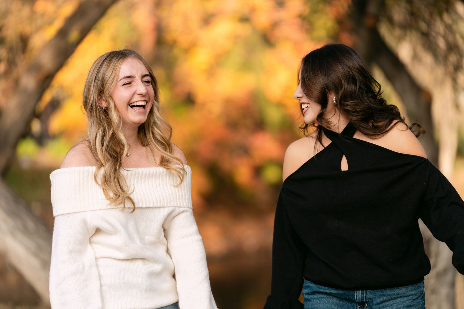 Two people share a joyful moment outdoors during fall with autumn colors in the background.