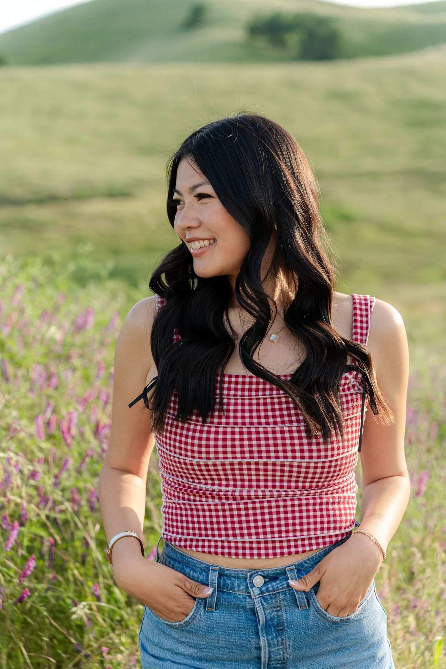 Summer portrait in gingham top and denim against rolling green hills background.