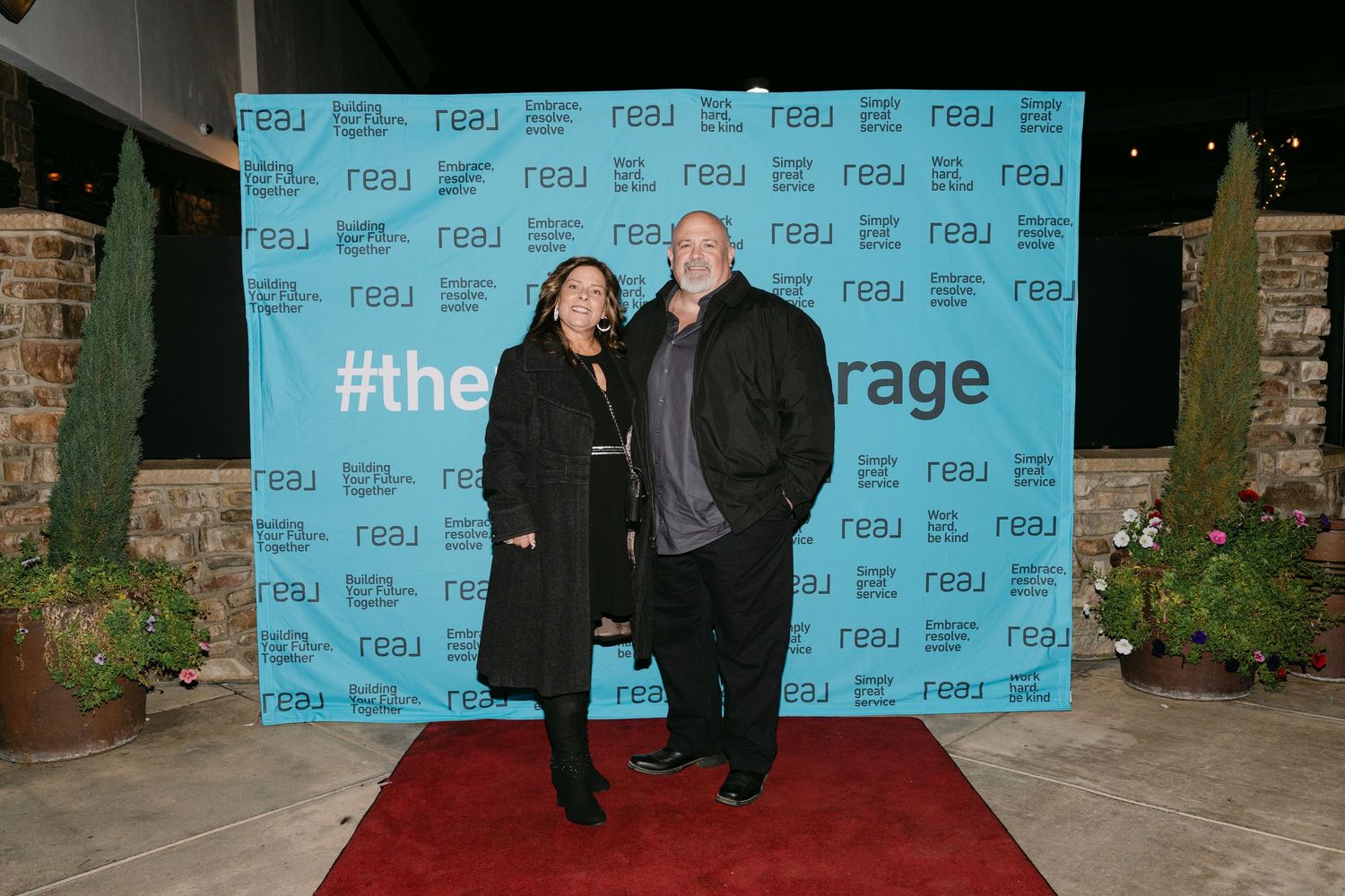 A step-and-repeat photo backdrop with blue branding at a professional event.