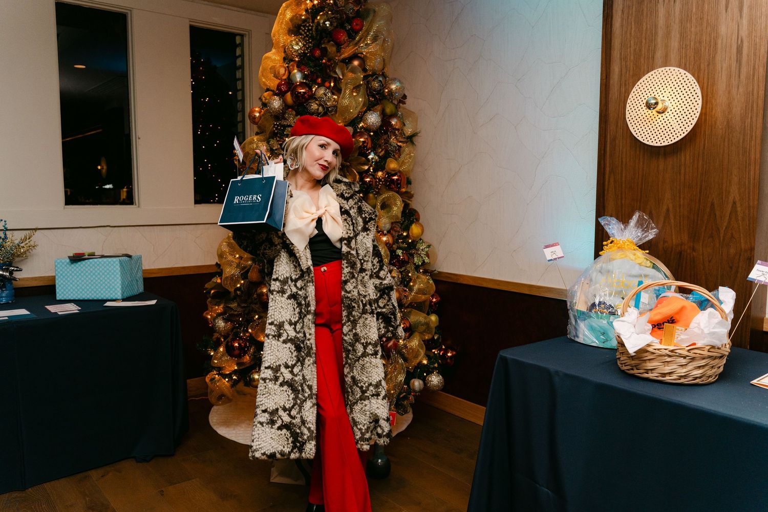An indoor event space decorated with Christmas trees and holiday decor for a celebration.