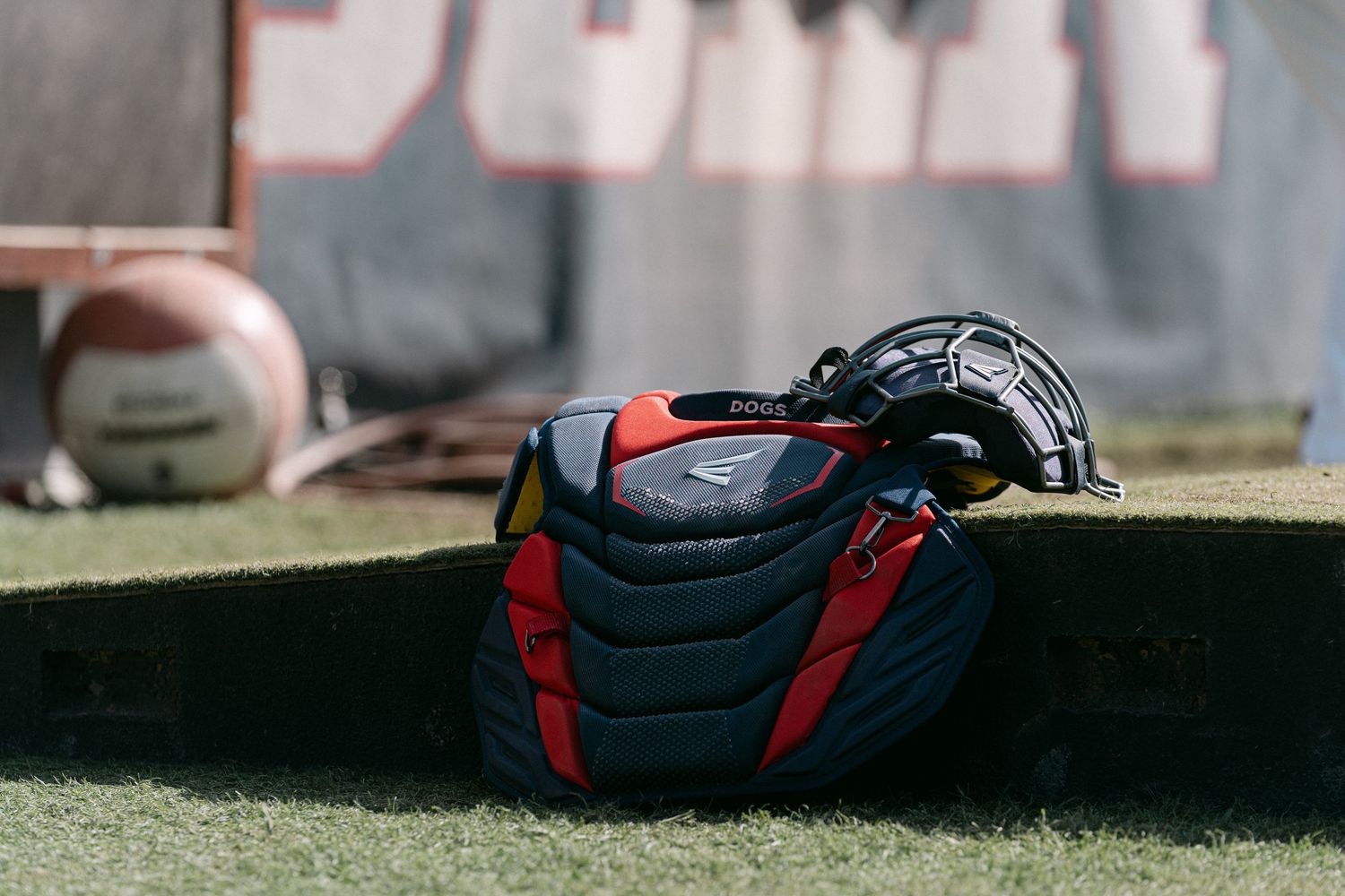 Black and red sports equipment bags lined up on grass field in outdoor setting.