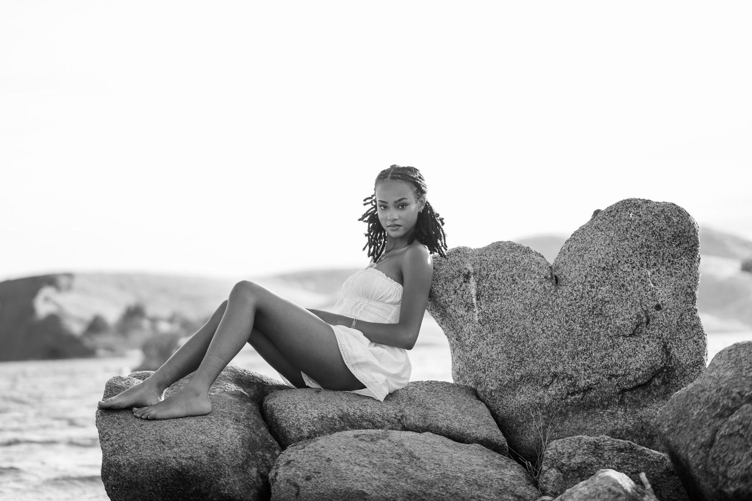 Artistic black and white portrait series captured on rocky beach landscape.