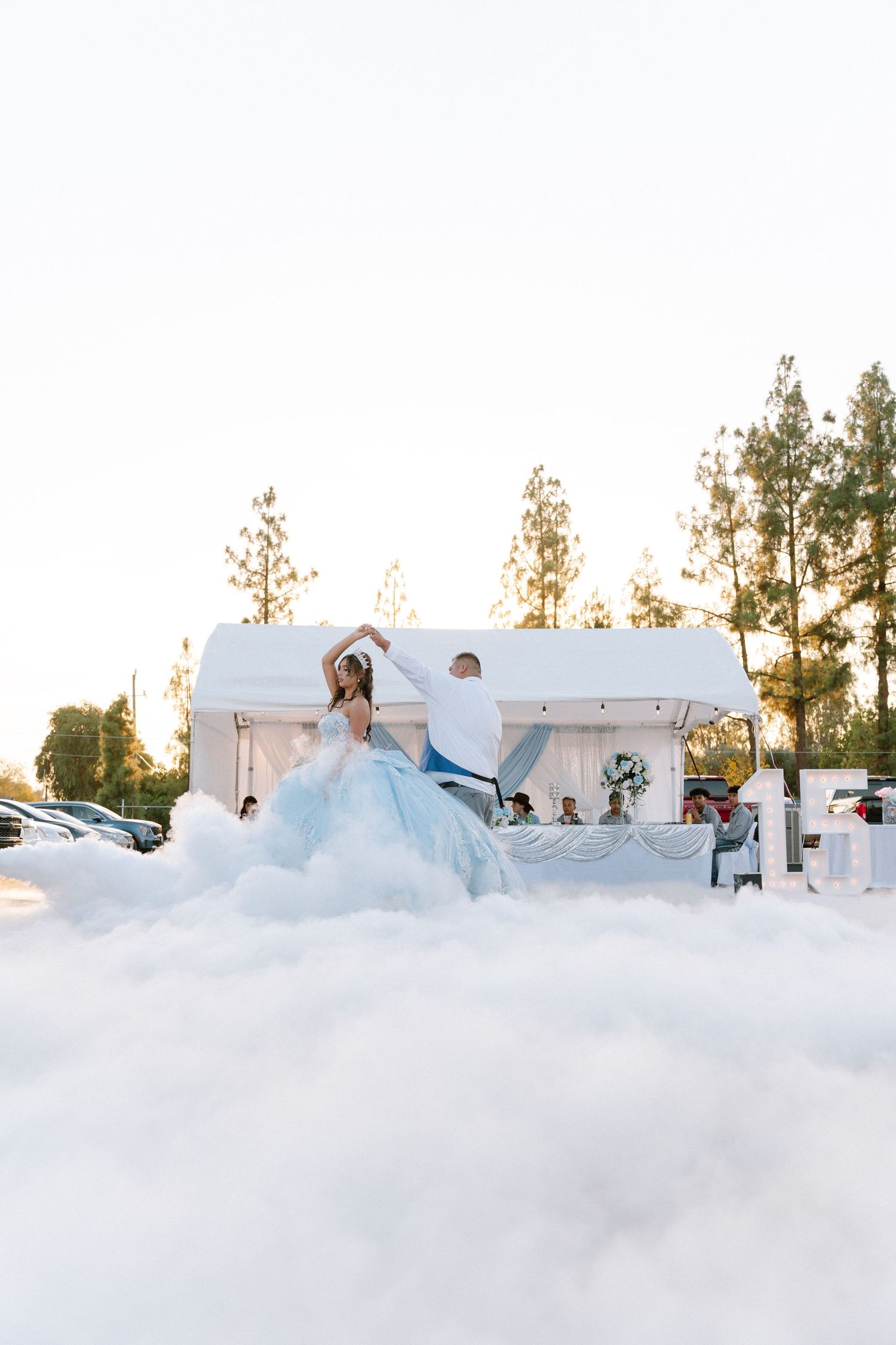 Wedding reception setup with white tents and ethereal fog creating a dreamy atmosphere at sunset.