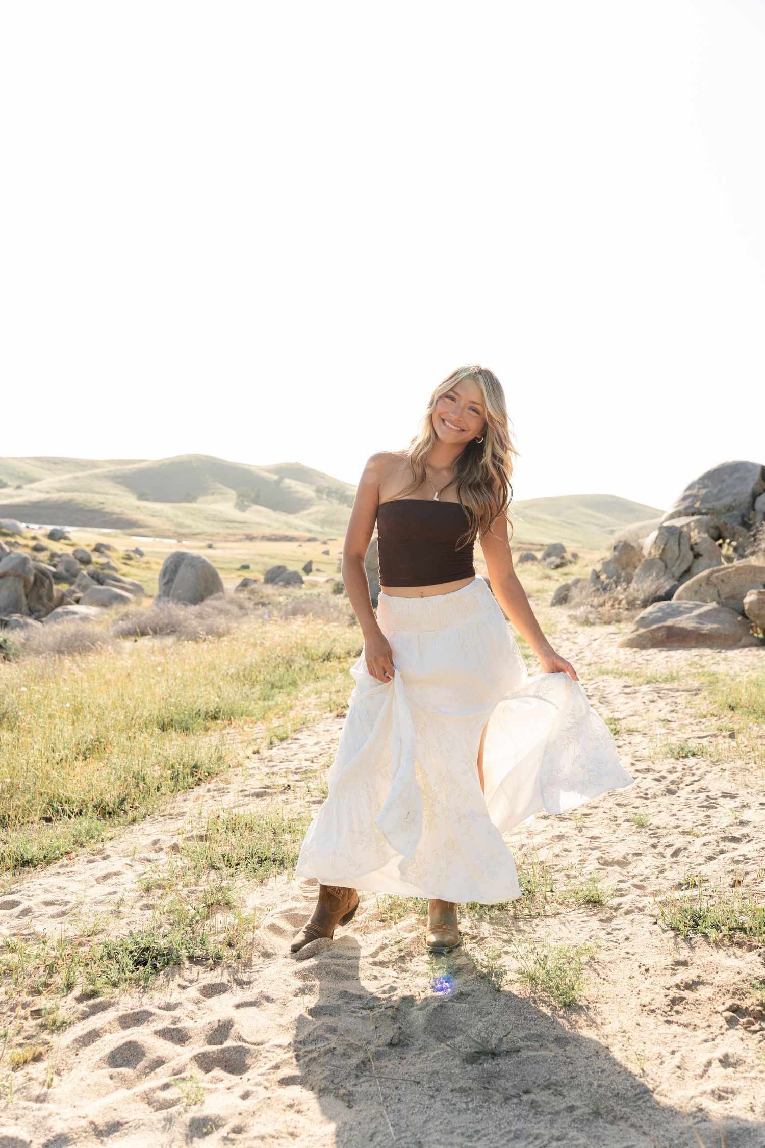 Fashion photography on sandy terrain featuring flowing white fabric and natural poses.