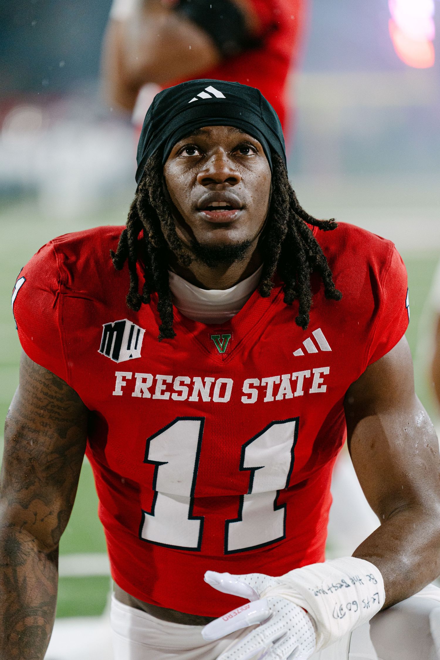Football player in red Fresno State uniform number 11 smiling on the field during a game.