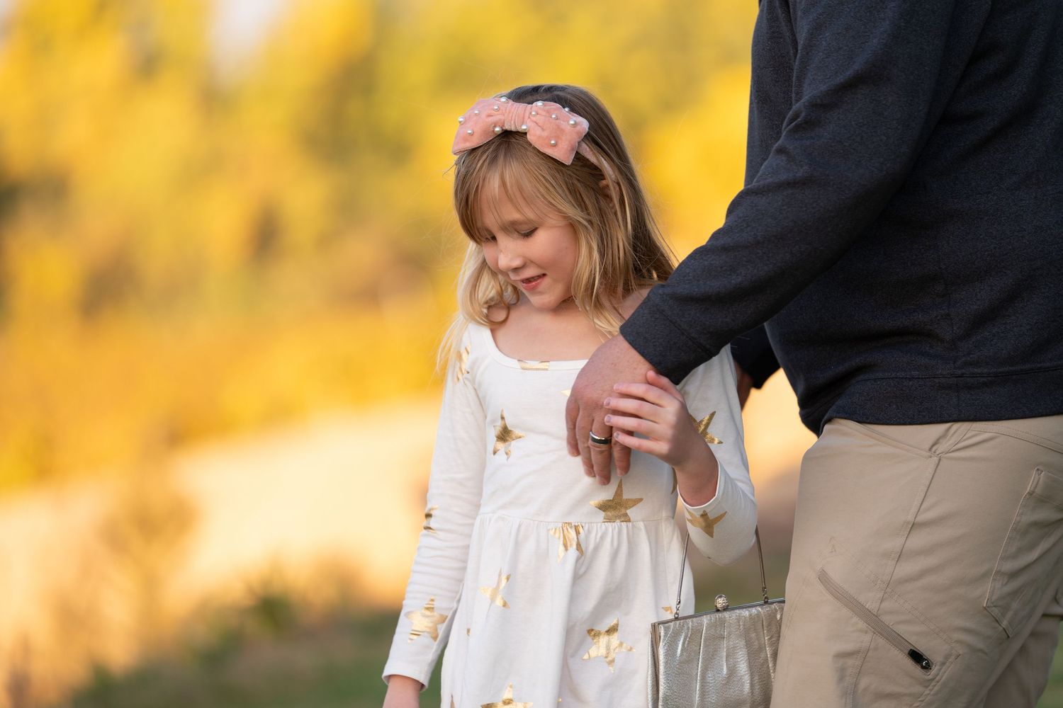 A touching moment between parent and child in a white dress against autumn colors.