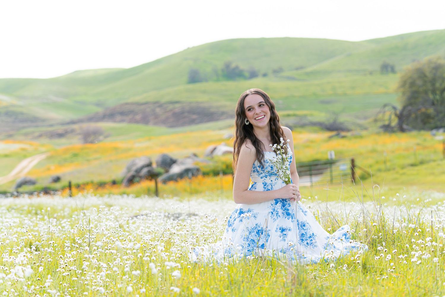 Dreamy springtime portraits in a field of white wildflowers with rolling hills.