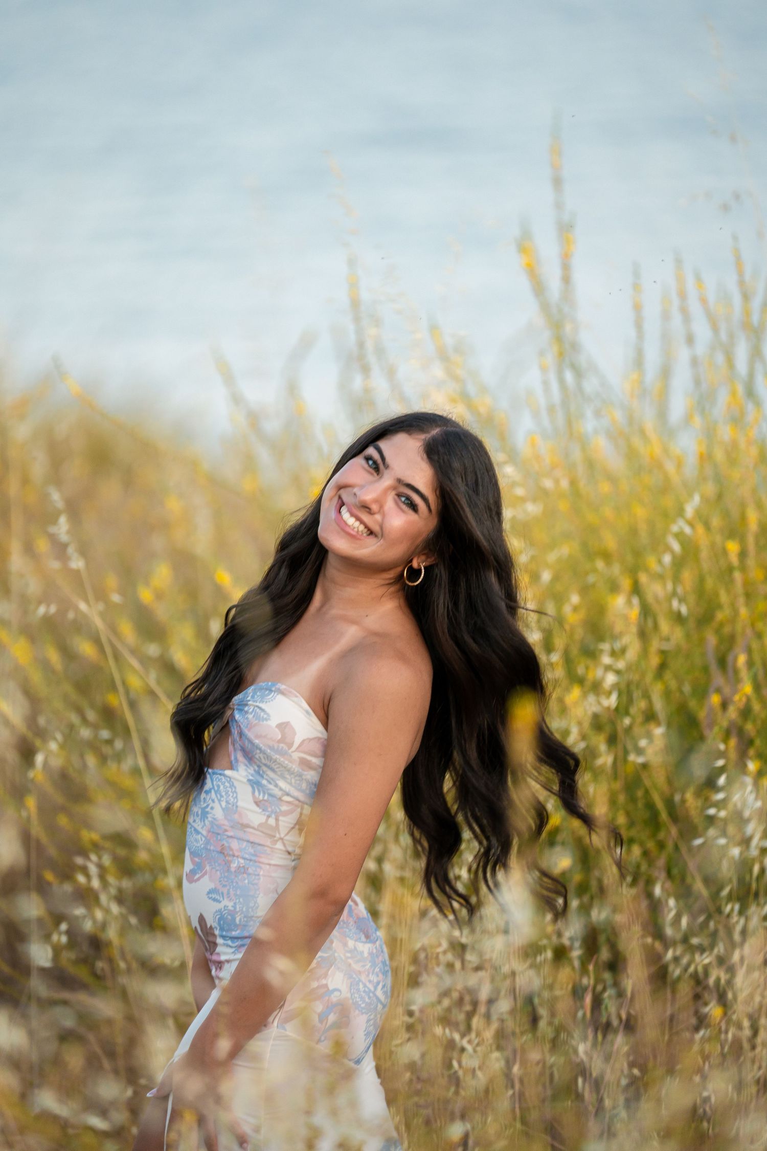 Ethereal portrait in a sparkly dress among tall golden grass during sunset.