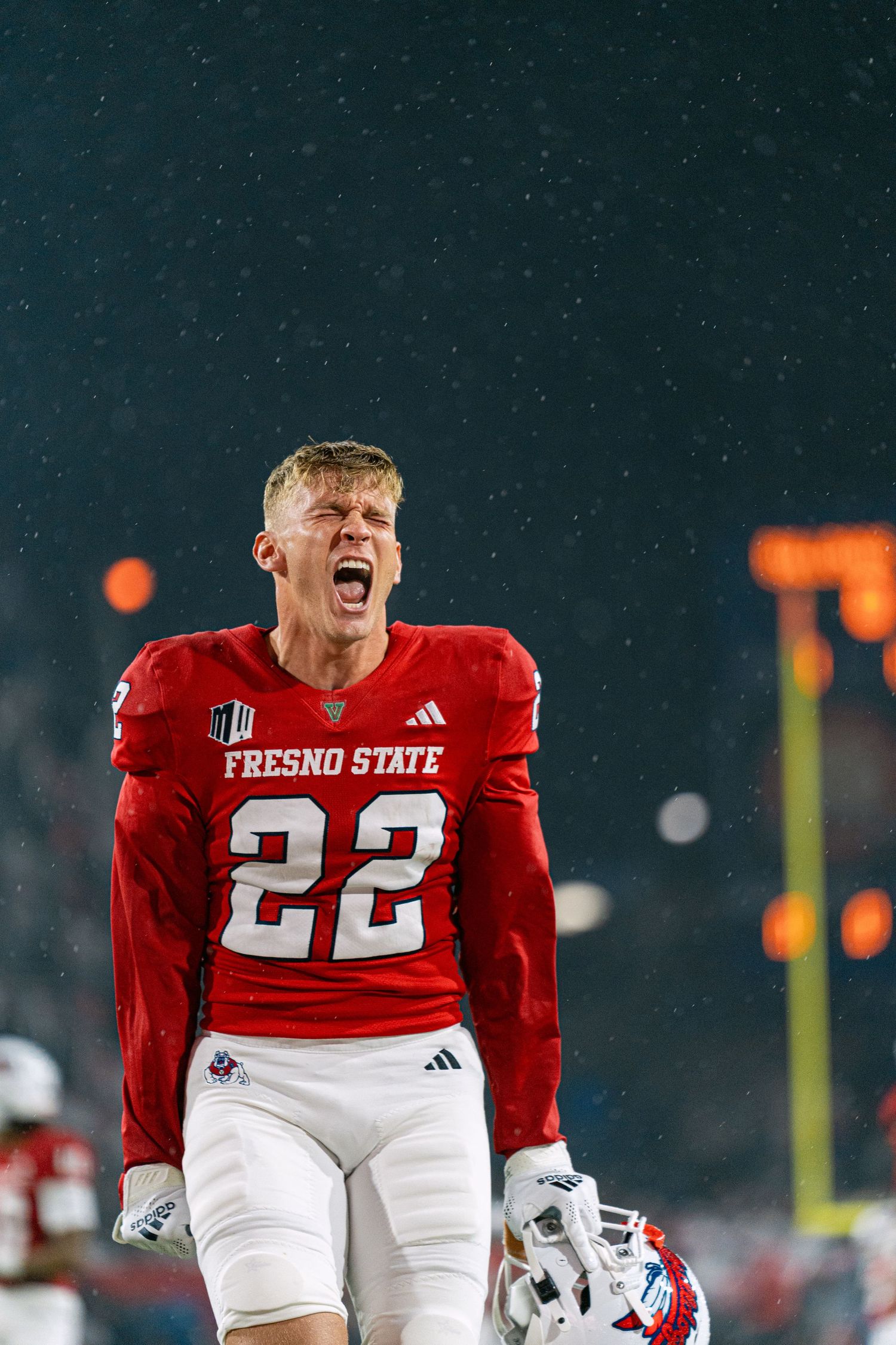 Fresno State football player in red jersey number 22 celebrates emotionally during nighttime game with stars visible.