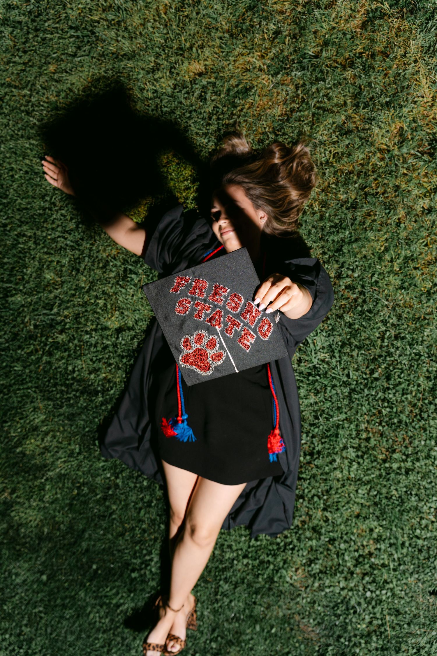 A sequence of photos showing someone in a black graphic t-shirt lying on grass against a green hedge background.