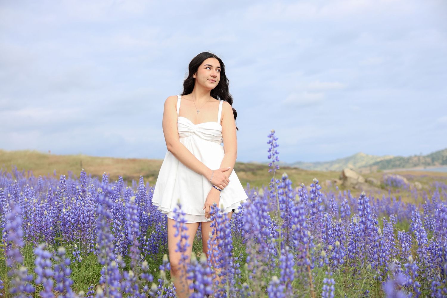 White dress contrasts beautifully against field of purple lupine flowers.