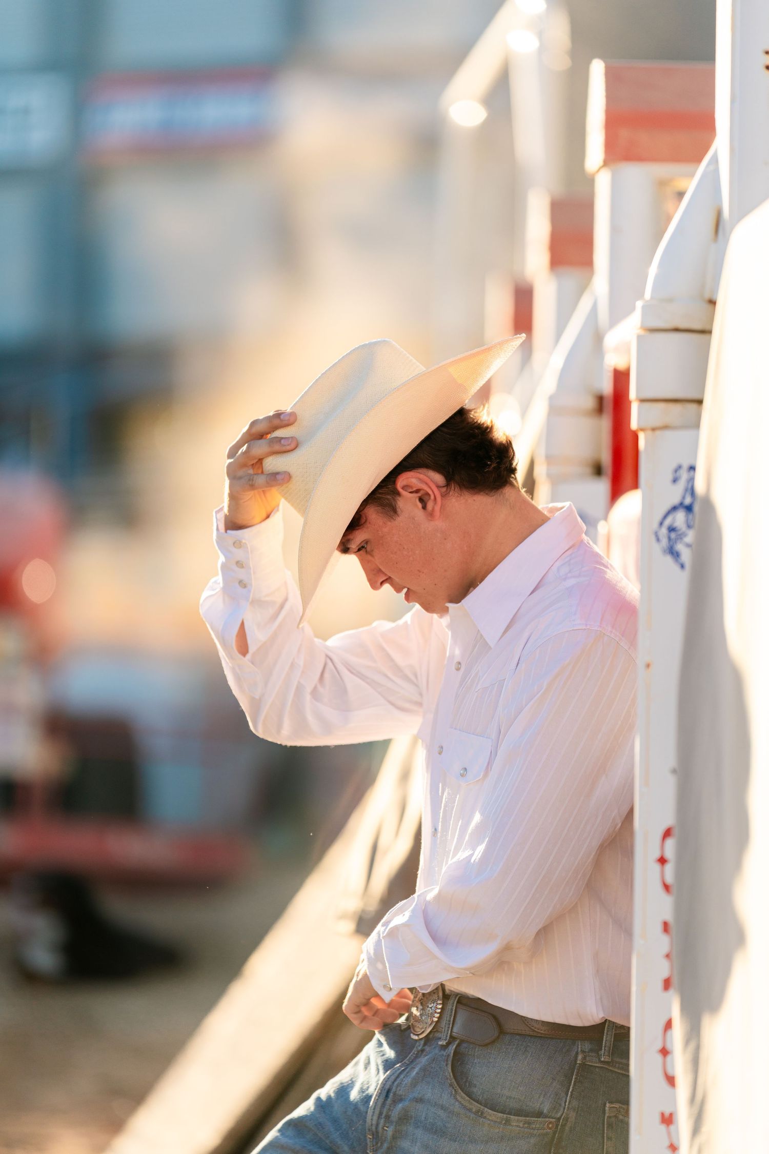 Person in white shirt and cowboy hat leans against white column in artistic poses.
