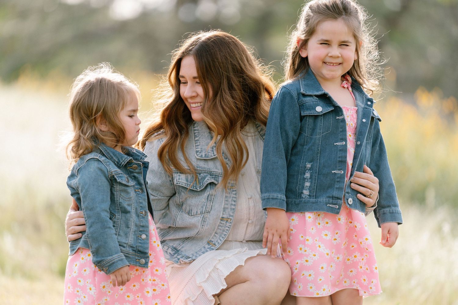 Casual family portraits in a natural setting with denim and white outfits.