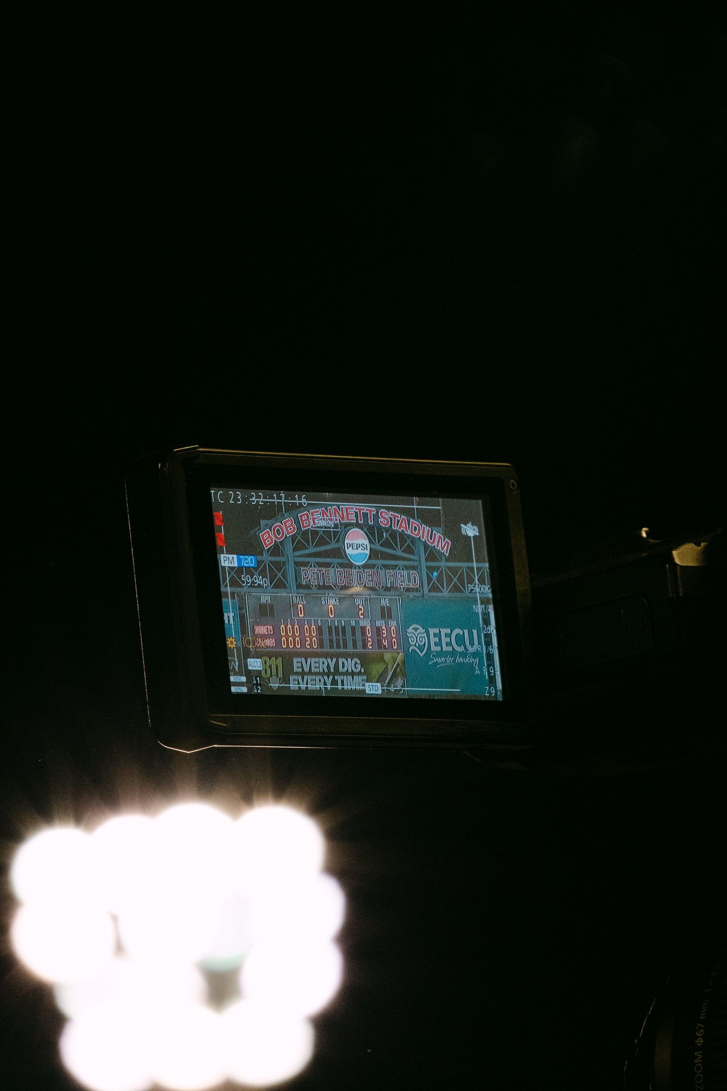 Illuminated digital scoreboard glowing against dark night sky at a sports stadium during a game.