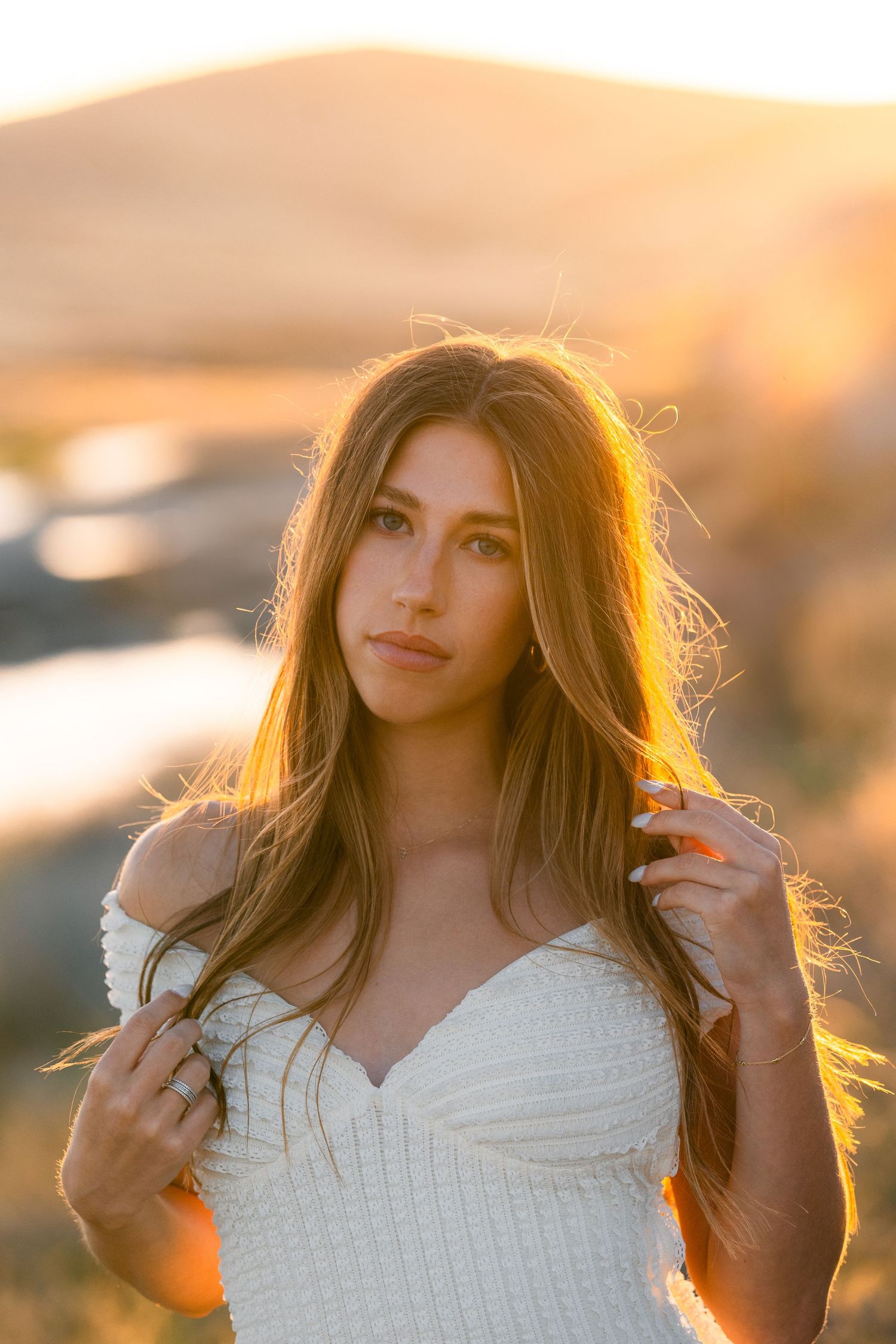 Portrait of a woman in white dress backlit by golden sunset light.