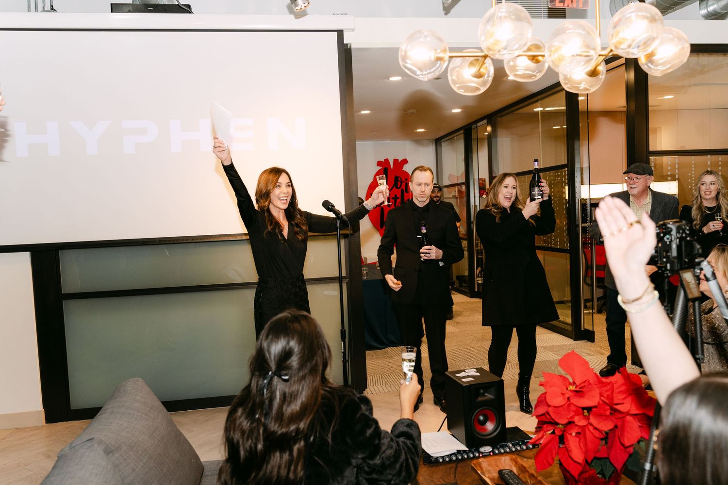 Event attendees gathered in a bright indoor space with raised arms.