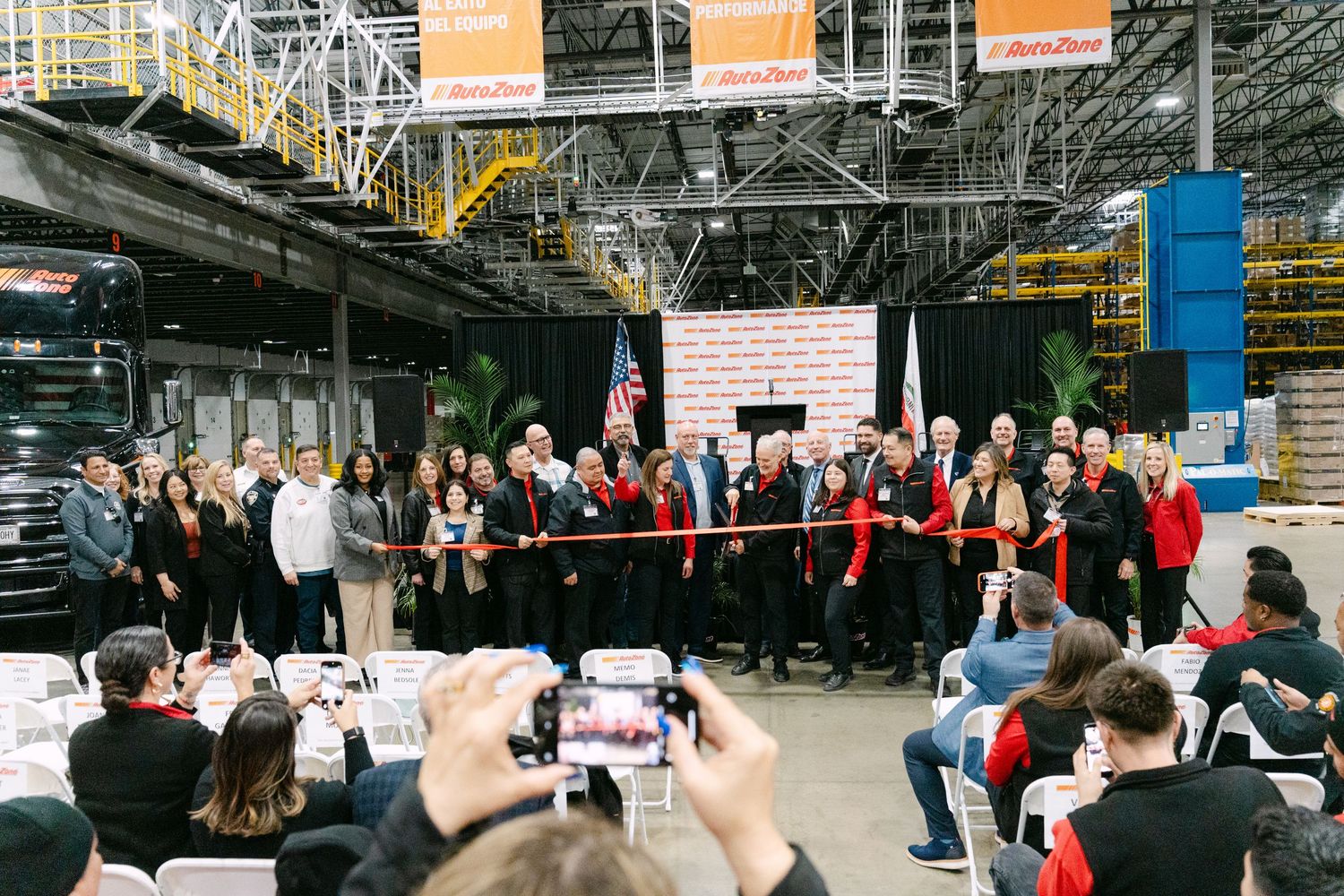 Panoramic view of a large indoor industrial space with metal structures and scattered groups of people.